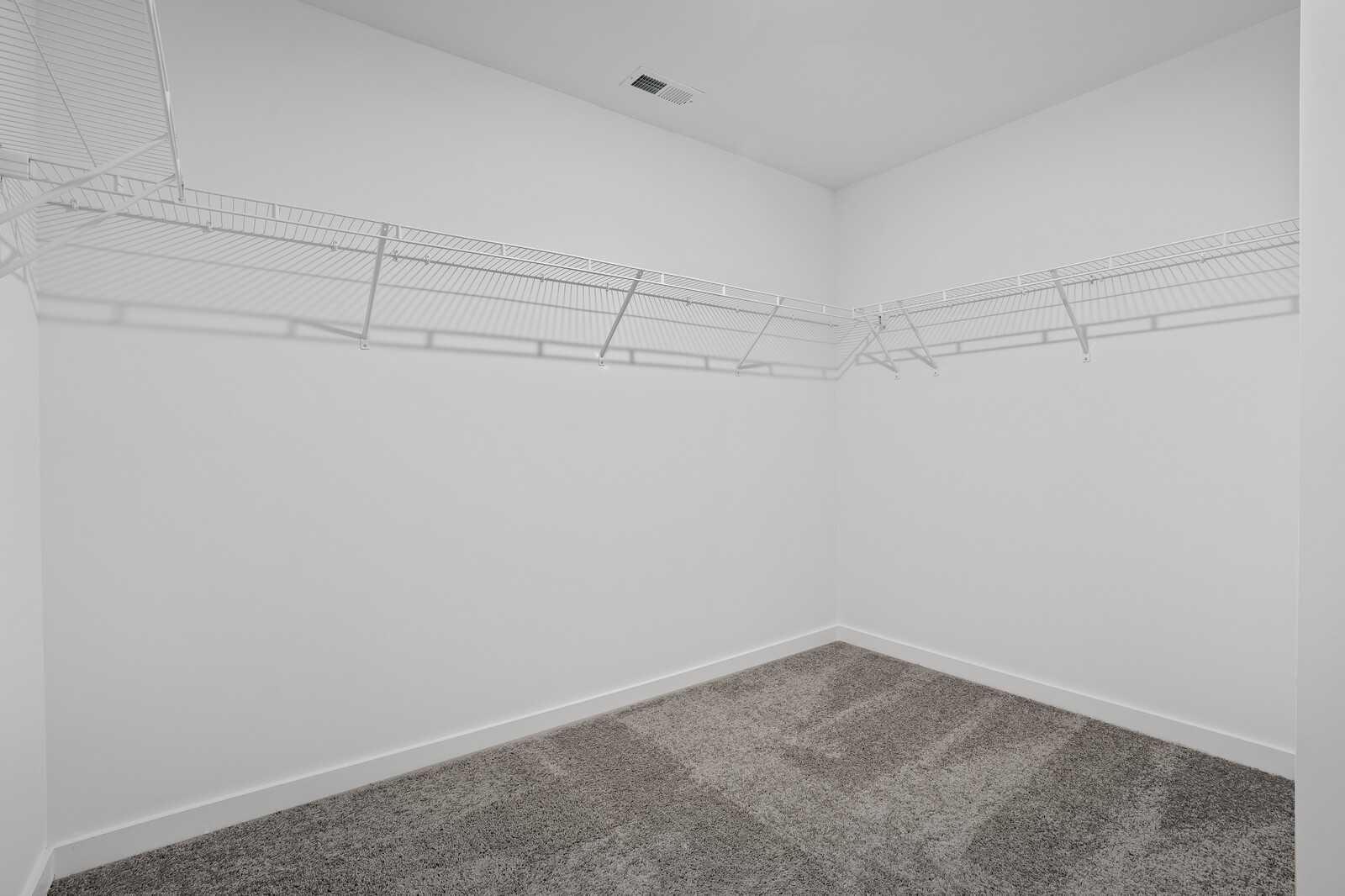 Spacious walk-in closet with wire shelving on white walls and carpeted floor in Davidson Homes The Logan C, White House, TN