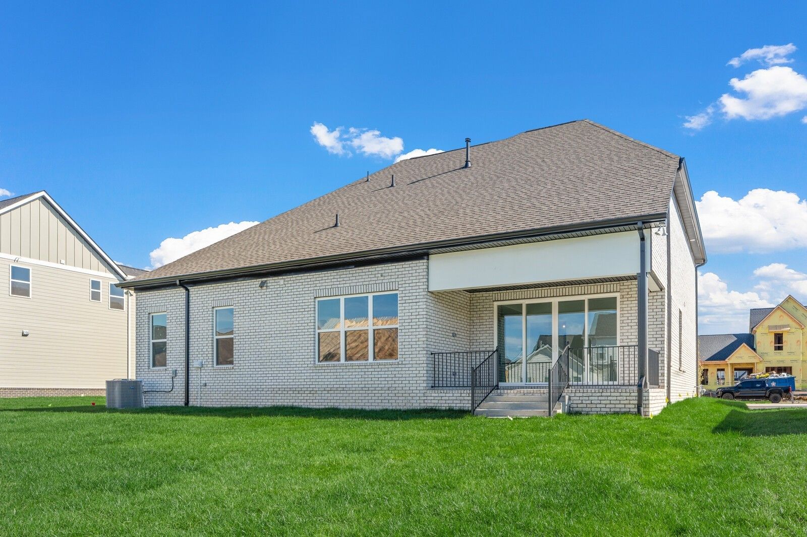 Rear view of two-story brick home with covered patio, sliding doors, and lush green yard in Shelton Square, Murfreesboro, Tennessee