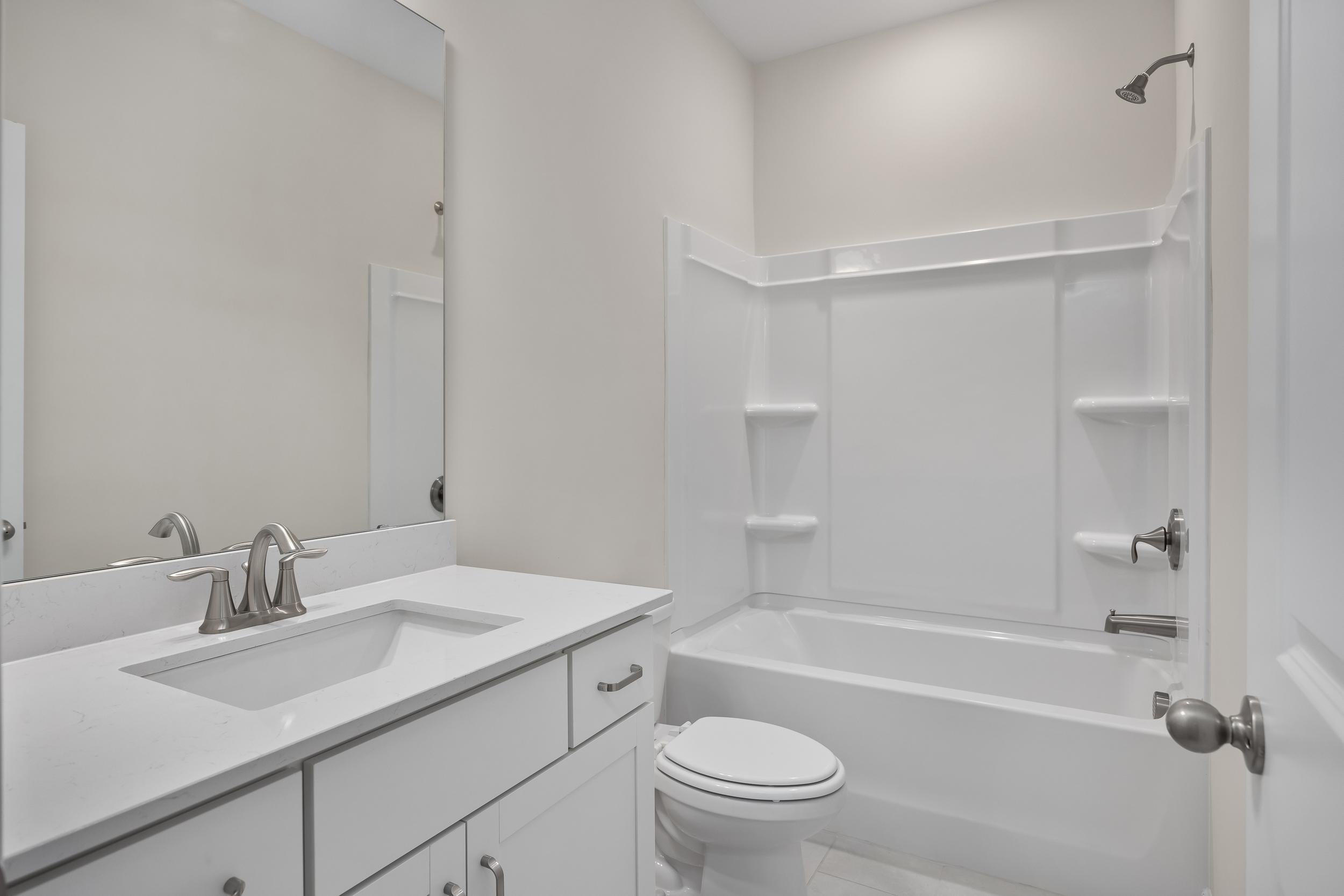 Spacious bathroom in The Beech A by Davidson Homes featuring white vanity, single sink, large mirror, tub-shower combo, and toilet
