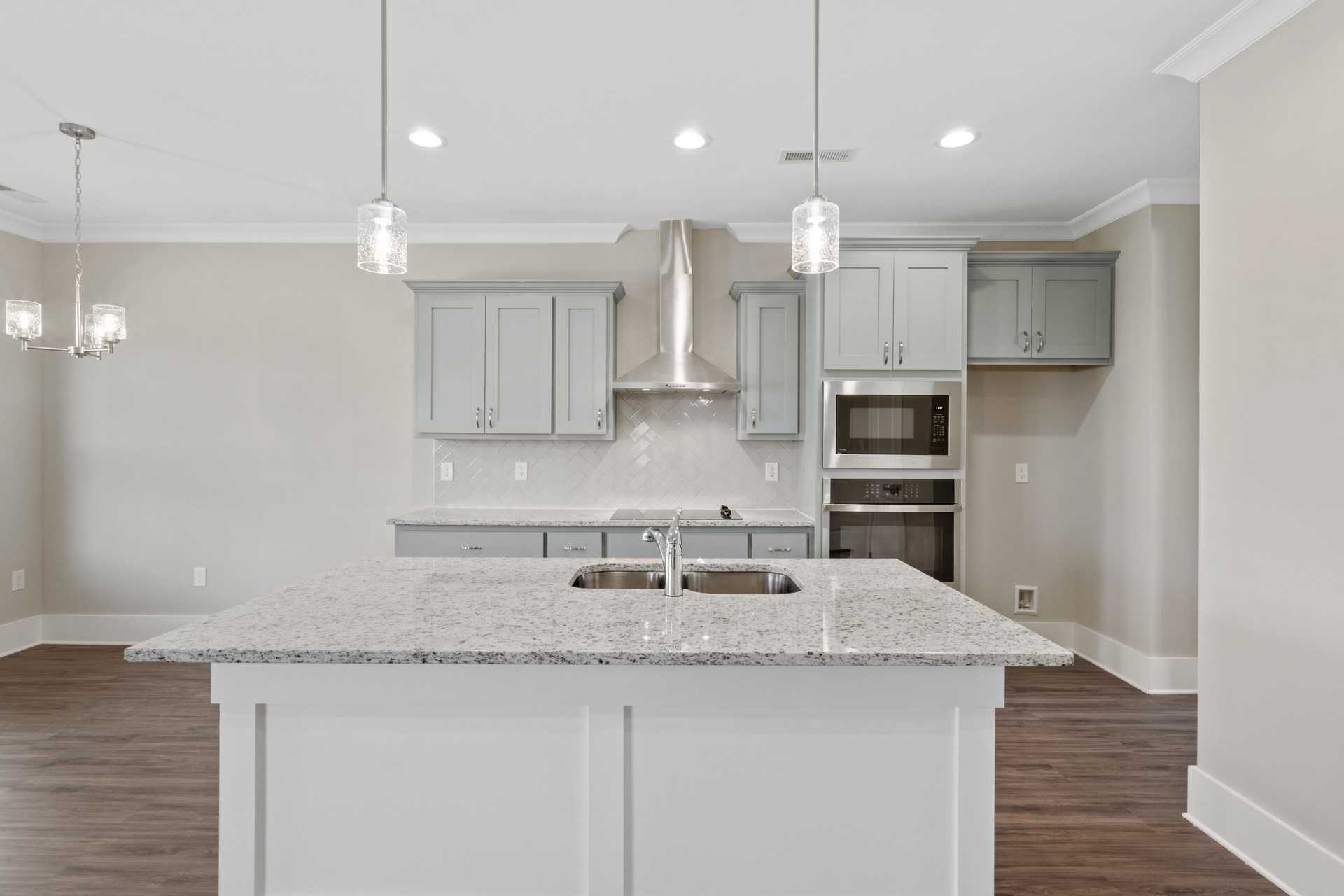 Spacious kitchen with white cabinets, gray quartz island, stainless steel appliances at Little Burwell Estates in Harvest, Alabama