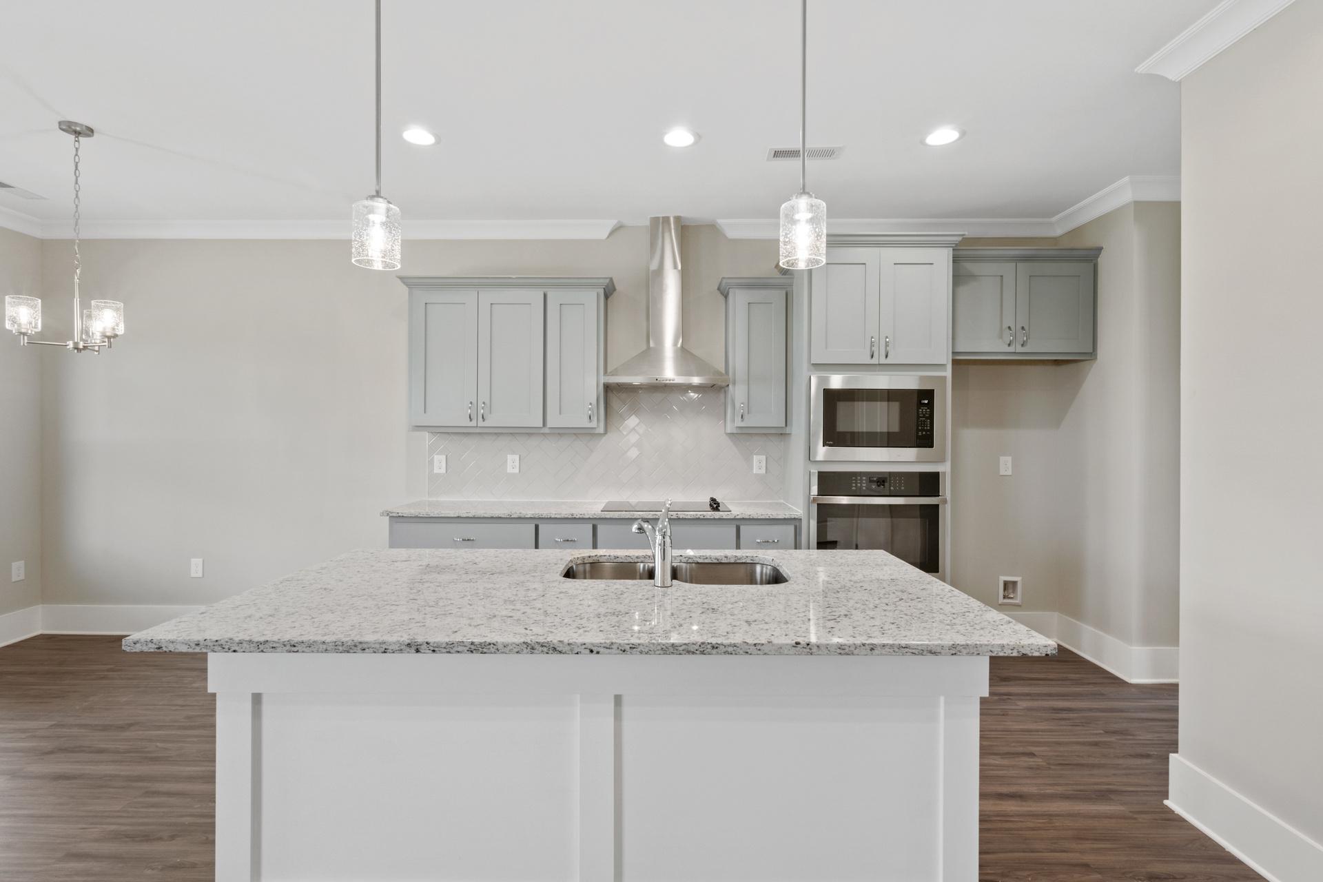 Spacious kitchen with white cabinets, gray quartz island, stainless steel appliances at Little Burwell Estates in Harvest, Alabama