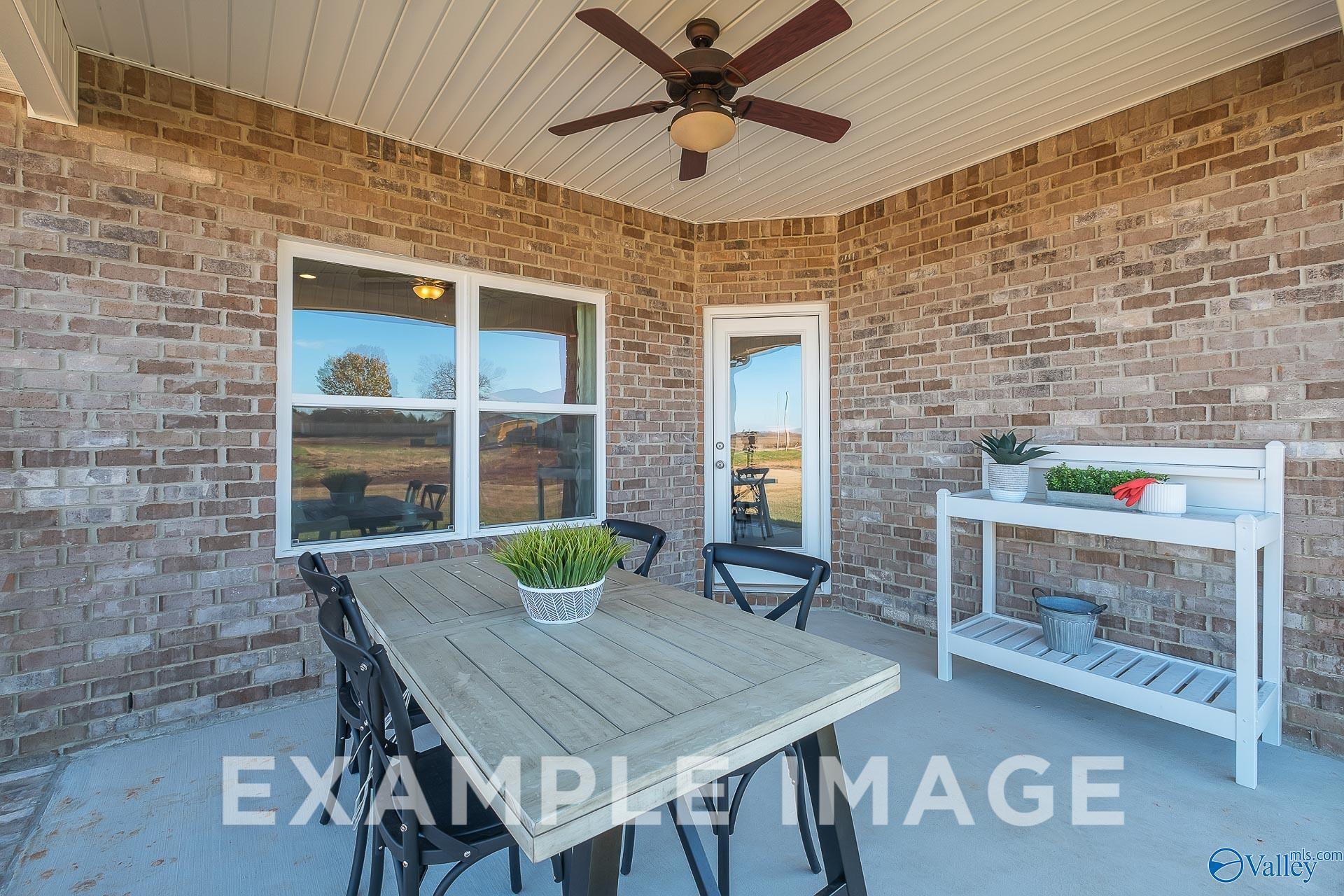 Covered brick patio with dining set and ceiling fan in The Everett B floor plan at The Meadows in Athens, Alabama.