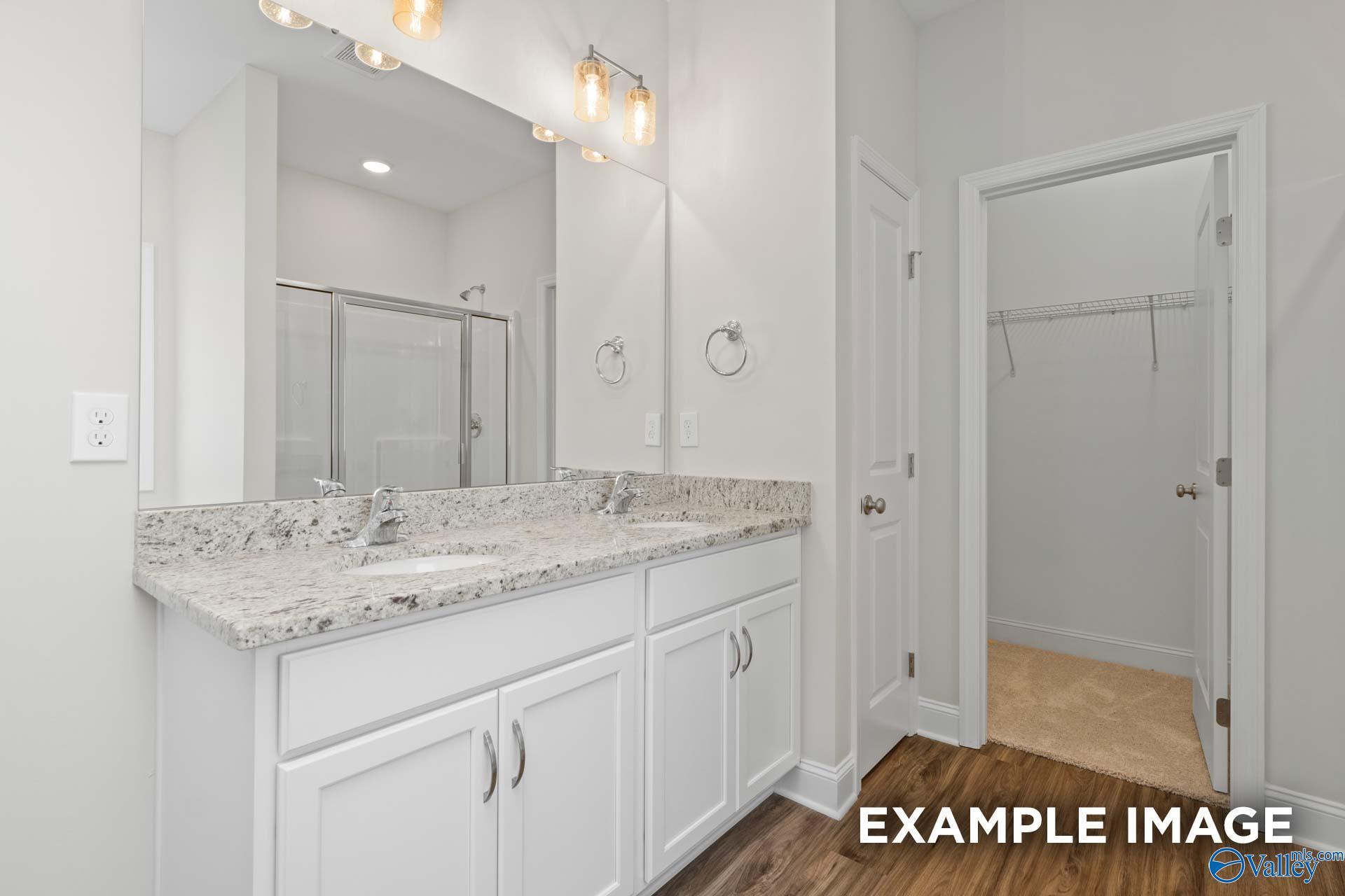 Elegant master bathroom featuring double vanity with quartz countertops, walk-in shower, and adjacent closet in Davidson Homes The Franklin B, Huntsville