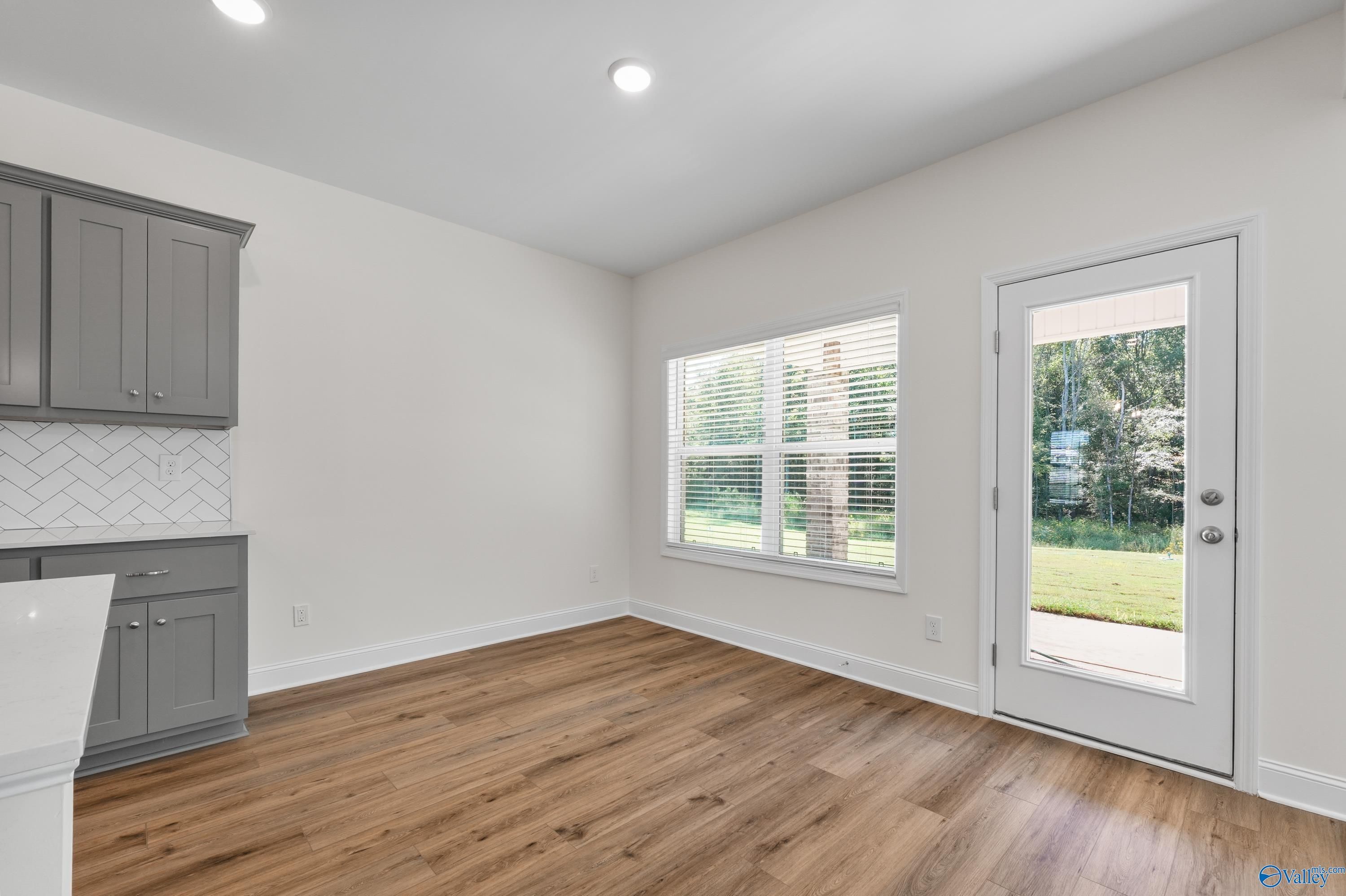 Bright kitchen with gray cabinets, subway tile backsplash, and backyard view via glass door in Davidson Homes Shelby A, Athens AL