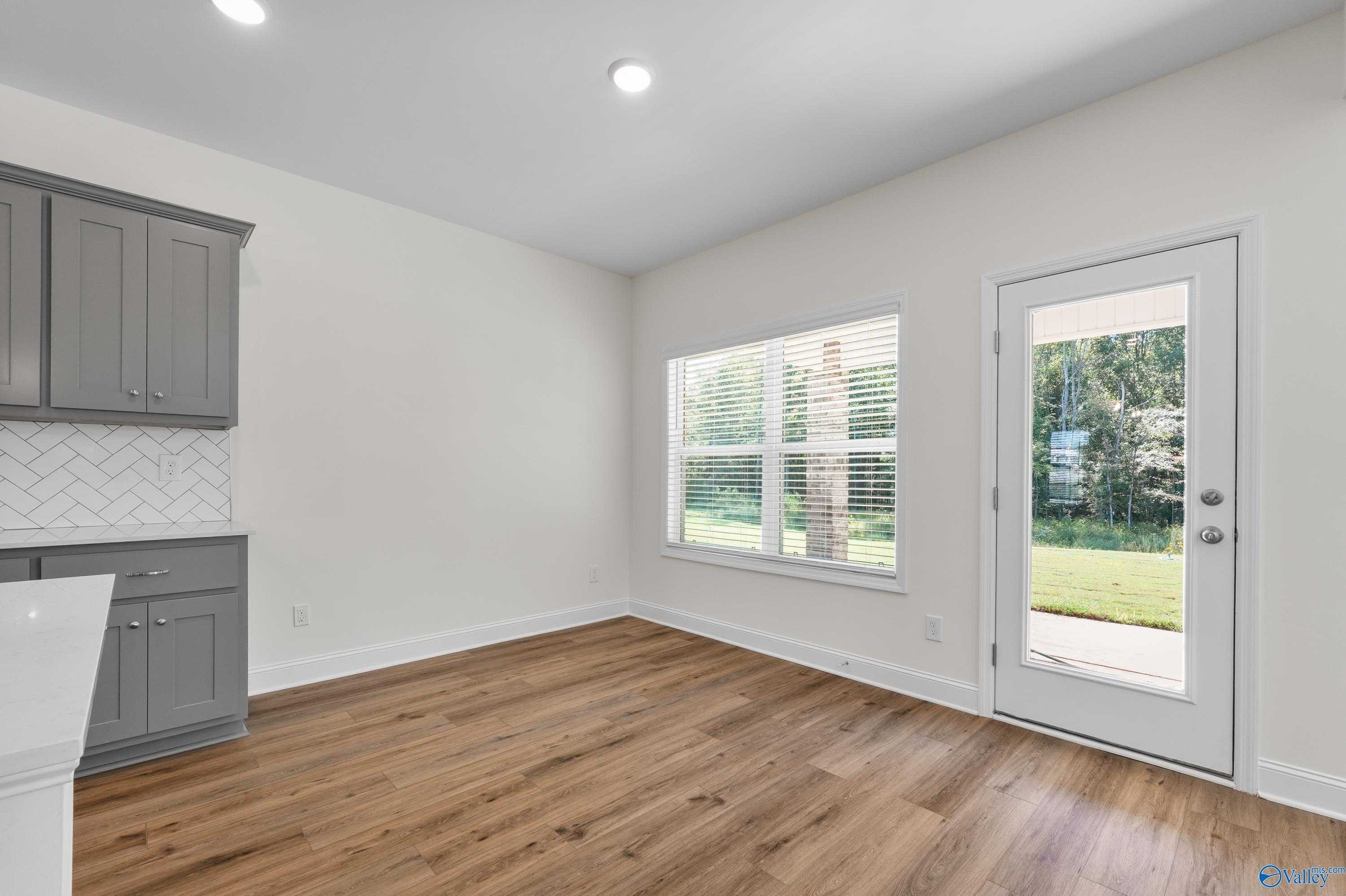 Bright kitchen with gray shaker cabinets, subway tile backsplash, and glass door to lush backyard in Davidson Homes Shelby A, Athens AL