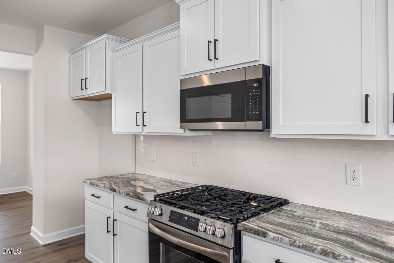 Modern kitchen with white cabinets, marble-look countertops, and stainless steel appliances in a Zebulon, NC home.