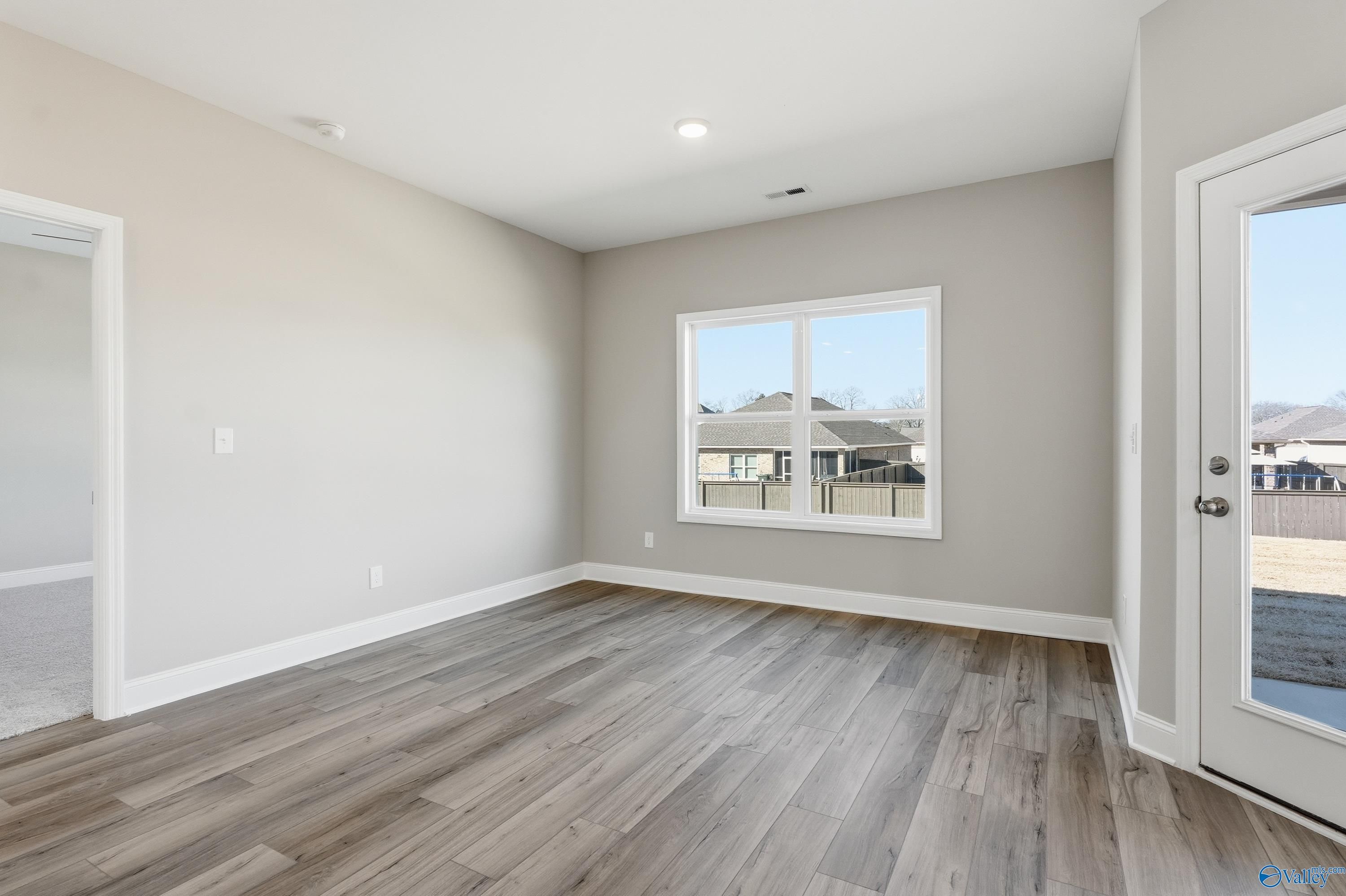 Bright living room with hardwood floors, large window, and sliding doors to fenced backyard in Davidson Homes The Franklin C, New Market, Alabama