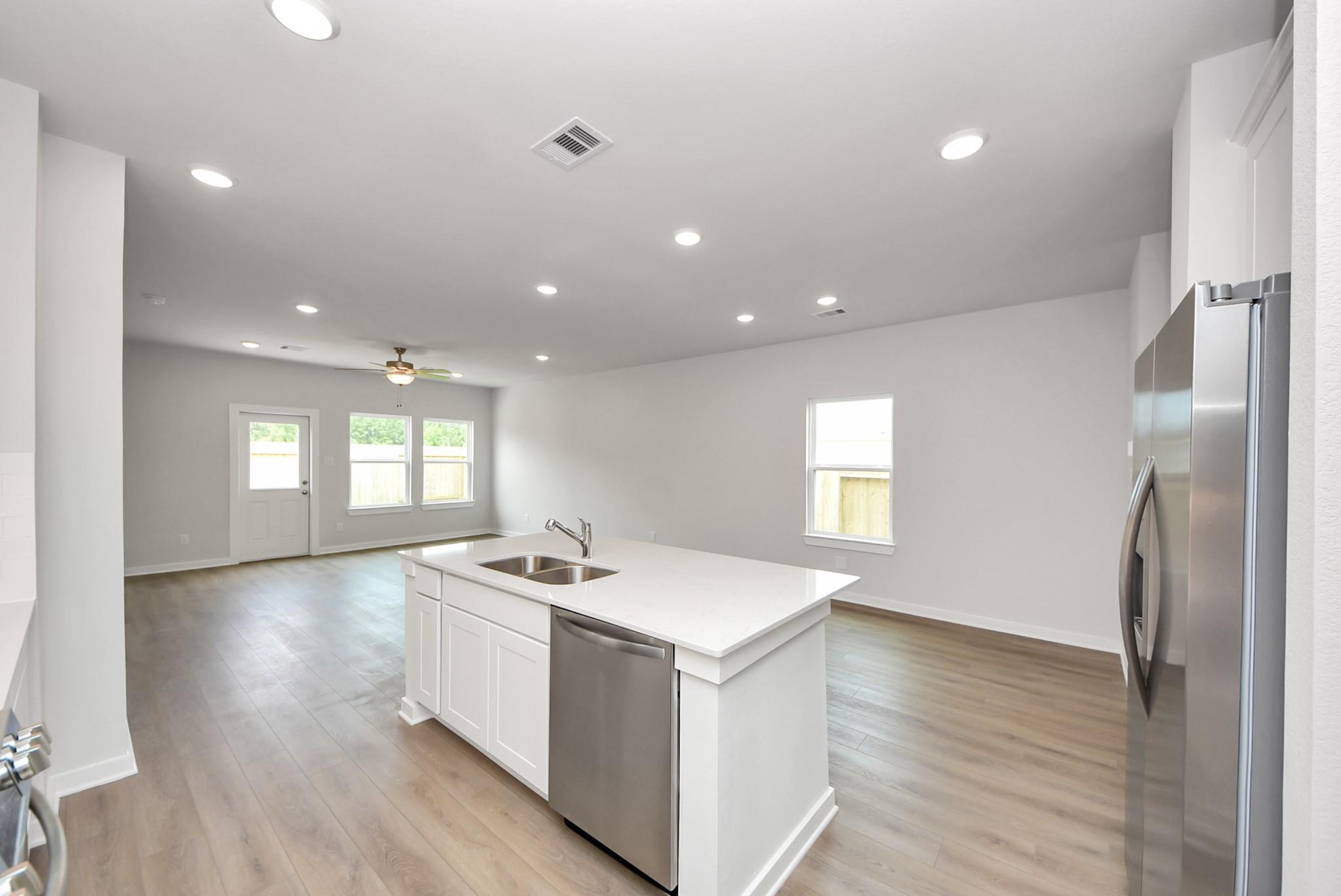 Open-concept kitchen with white island and stainless appliances in The Blanco E floor plan at The Villages at WestPointe.