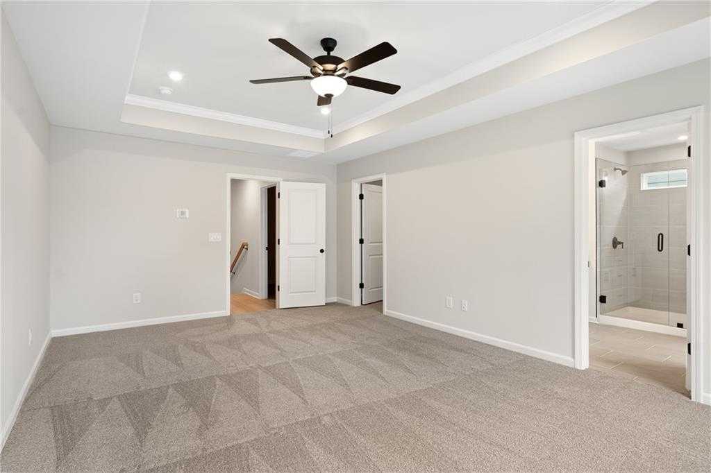 Spacious upstairs hallway with gray carpet, ceiling fan, and doors to bedrooms and bath in Davidson Homes The Marion A, Kennesaw, GA