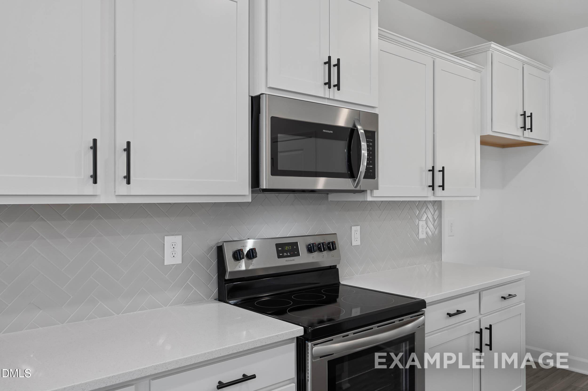 Modern white kitchen with shaker cabinets, stainless steel appliances, subway tile backsplash in The Willow D by Davidson Homes, Zebulon, NC