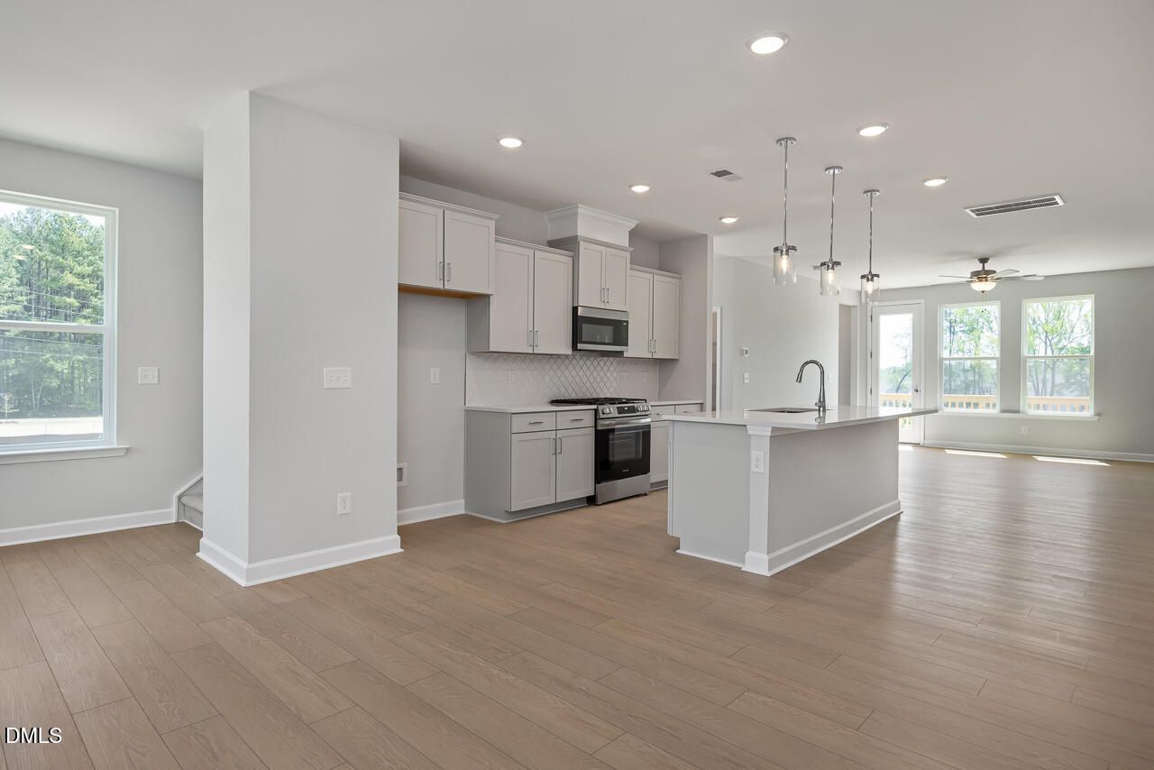 Modern open-concept kitchen with white cabinets and island in The Mitchell floor plan at Camden Park, Knightdale, NC.