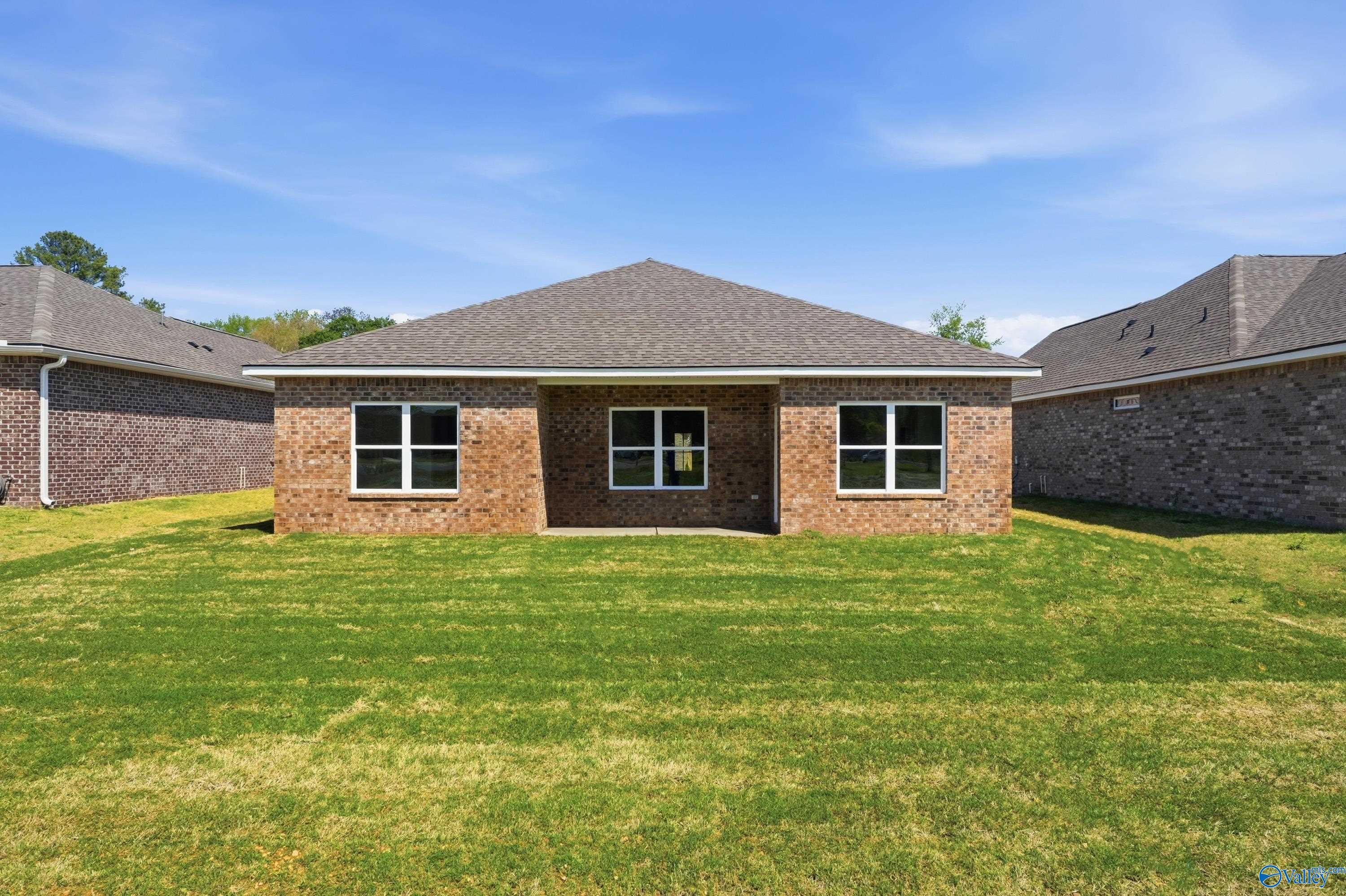 Back view of The Asheville floor plan, a 1-story brick home with a grassy backyard in Jaguar Hills, Huntsville, Alabama.