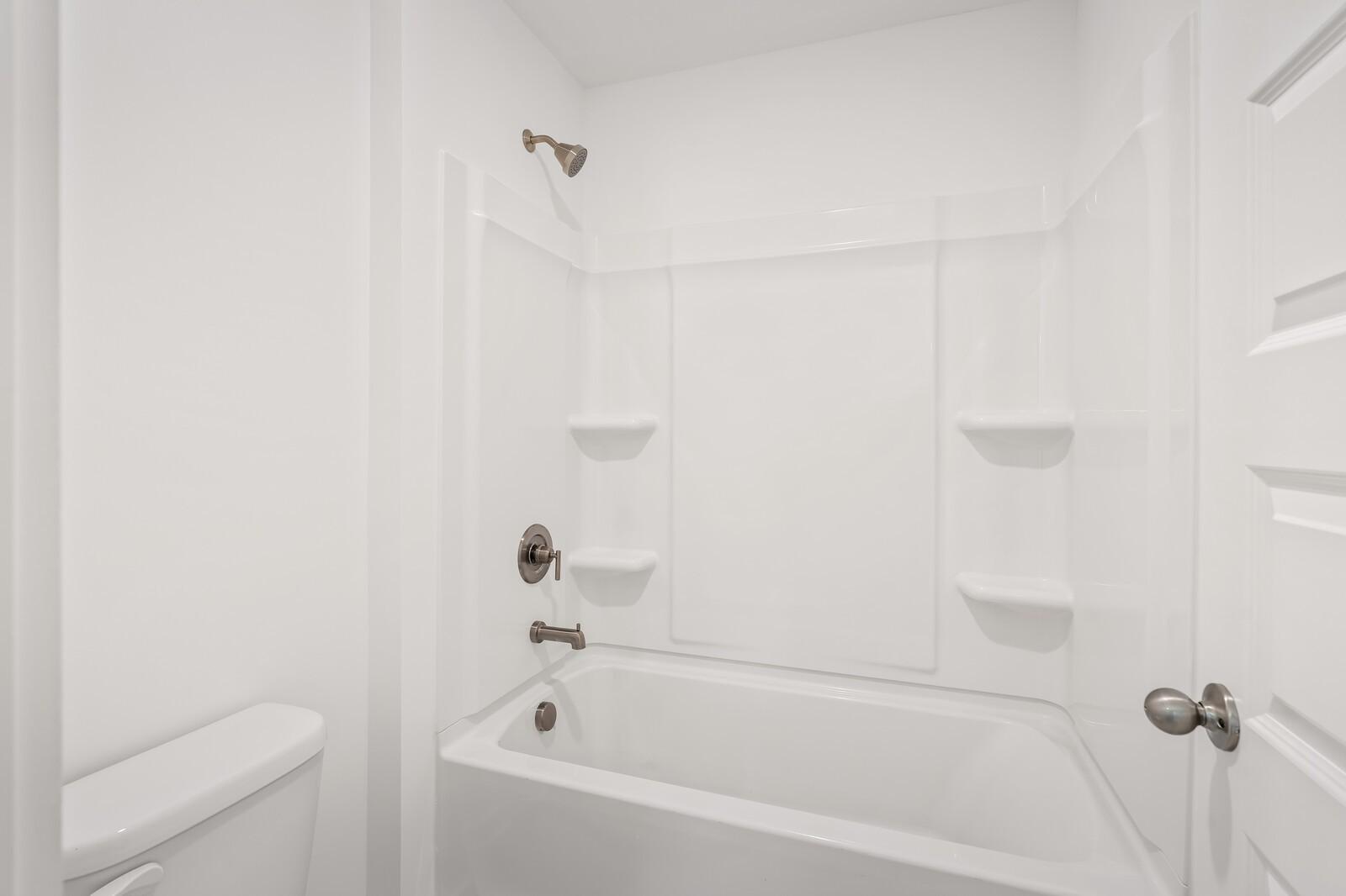 Bright white secondary bathroom with tub, tiled shower, and bronze fixtures in Davidson Homes The Ash C, Mt. Juliet, TN