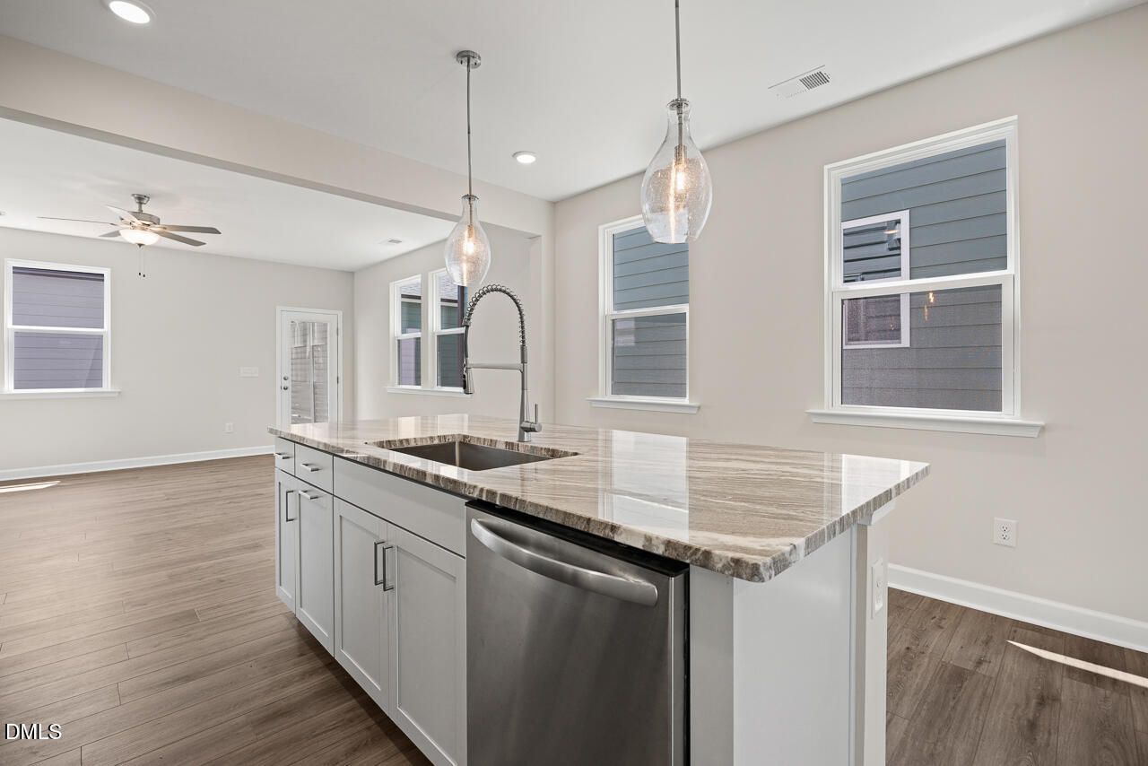 Modern kitchen island with granite countertops and stainless appliances in The Alexander C plan at Forestville Yard.