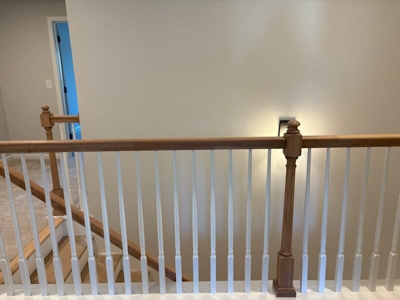 Elegant wooden staircase with white balusters and beige walls in 2-story Cary A home, Davidson Homes, Lake Shore, Winder, Georgia
