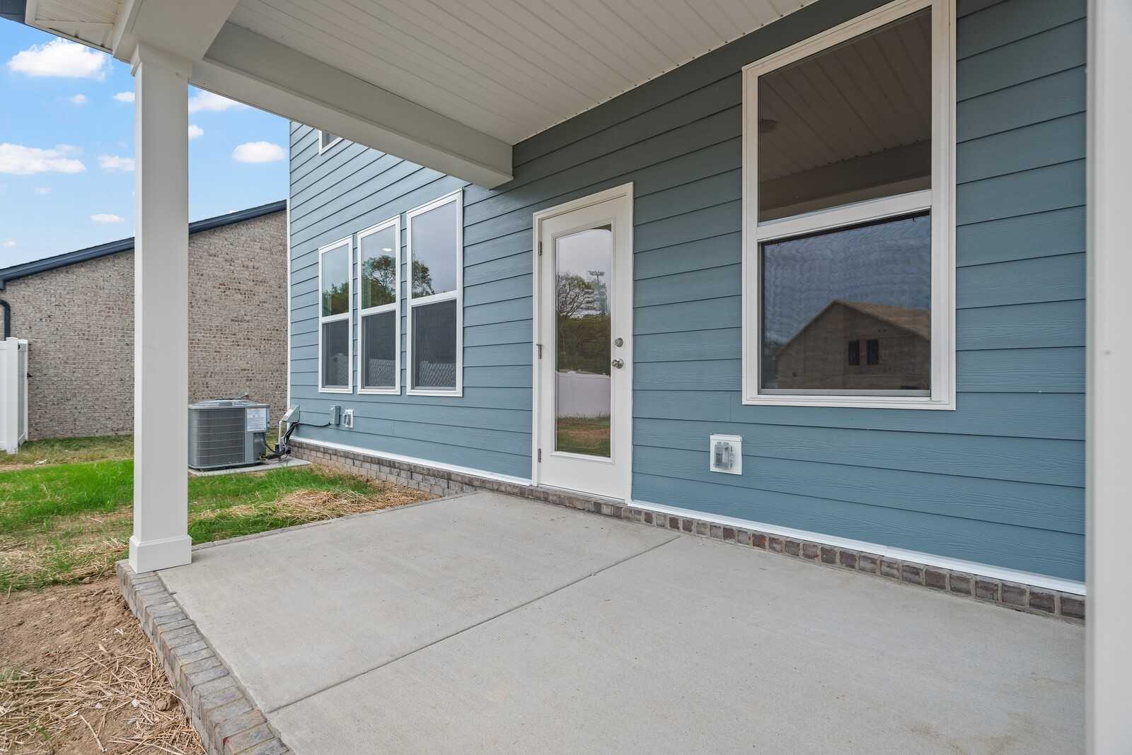 Covered patio with French doors, large windows, and blue siding on Davidson Homes The Logan C in Woods Crossing, Gallatin, TN