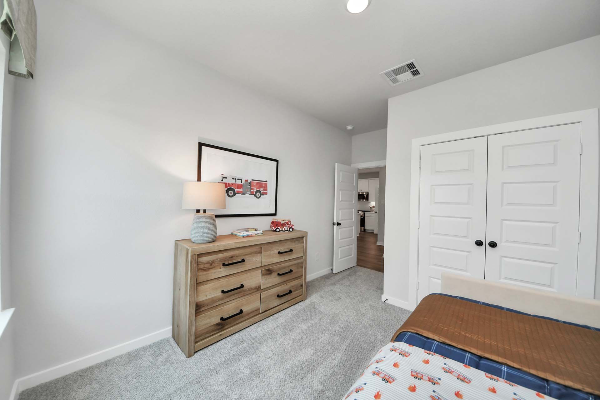 Cozy bedroom in a Davidson Homes floor plan at Enclave at Newport in Crosby, TX featuring a wood dresser and kids decor.