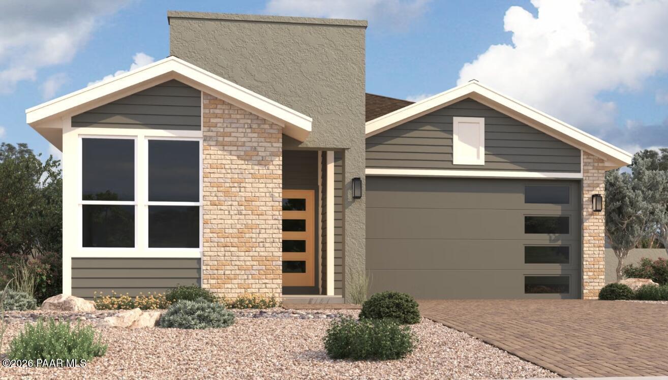 Modern 3-bedroom ranch home with brick facade, 2-car garage, large windows, and desert landscaping in Prescott, Arizona