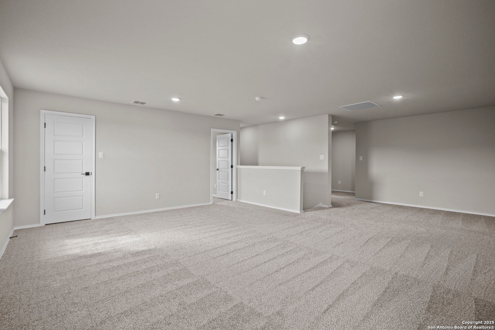 Spacious upstairs bonus room with beige carpet, white doors, and overlooking railing in Davidson Homes The Douglas F, San Antonio