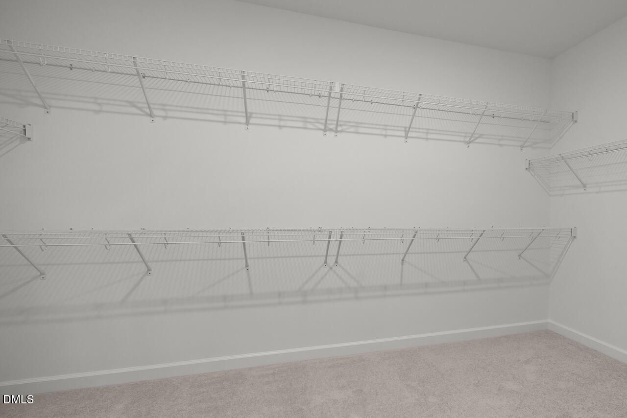 Walk-in closet with white wire shelving in the Primary Bedroom of The Birch II E at Sage on North Main, Wake Forest.