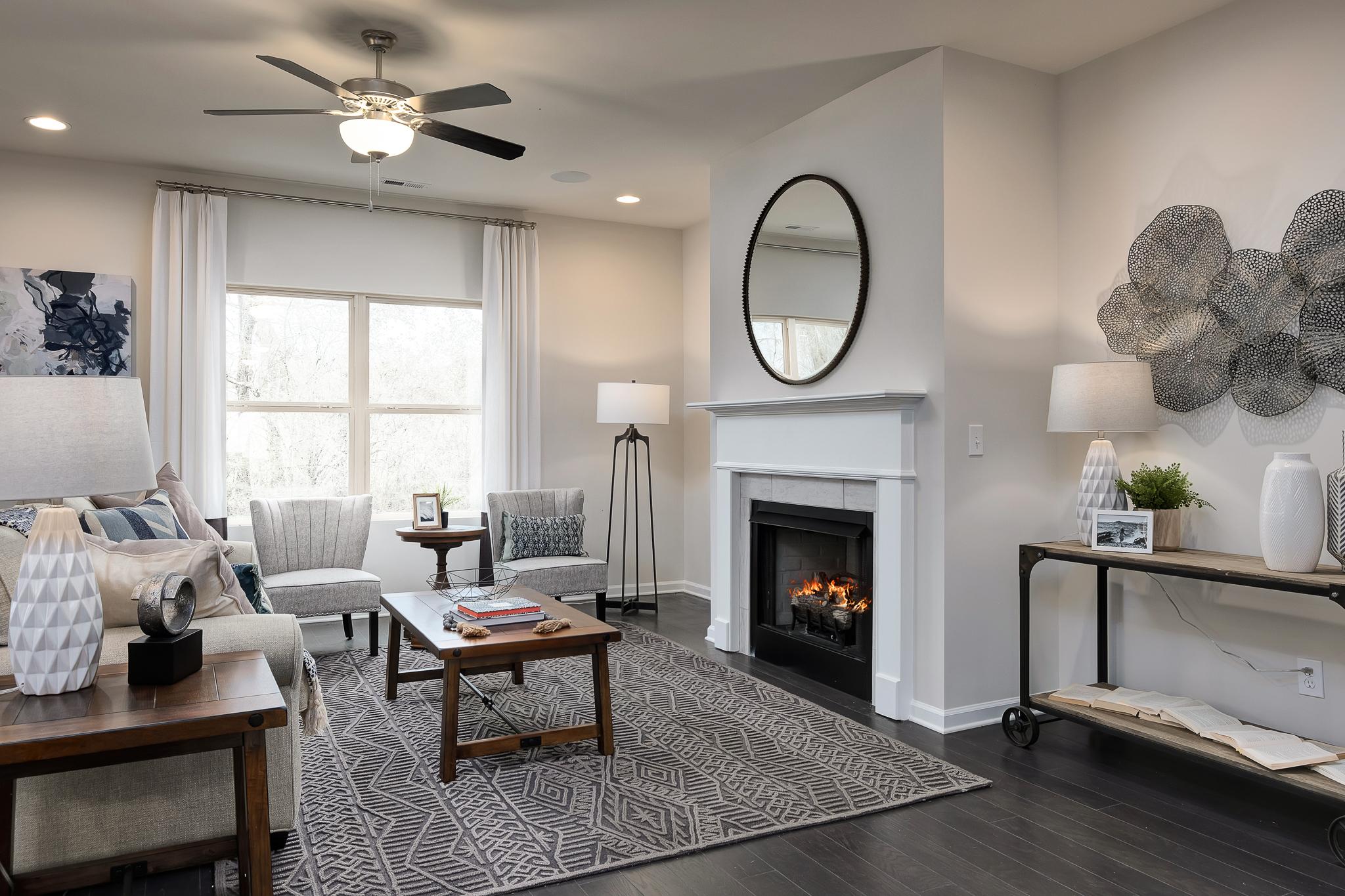 Cozy living room at The Reserve at Overton in Hampton Cove, Alabama with fireplace, hardwood floors, round mirror, and modern seating