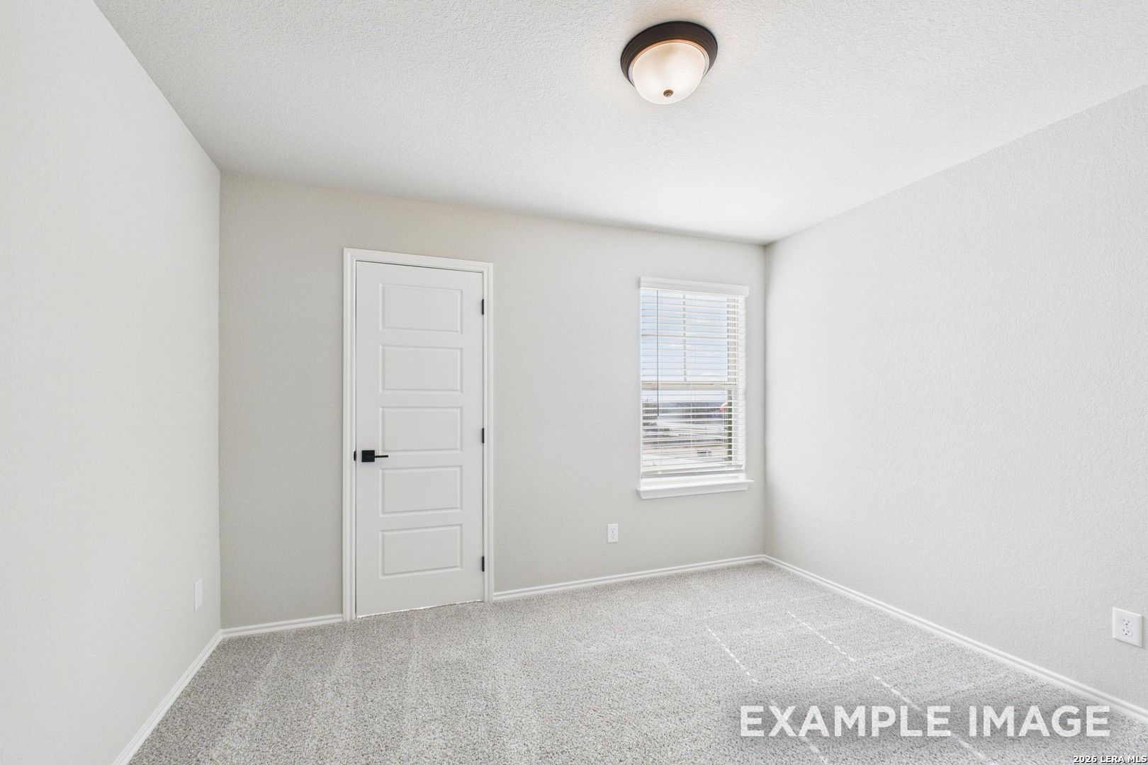 Bright, carpeted bedroom with neutral walls and a closet door in The Charlotte B floor plan at Cedar Heights, San Antonio.