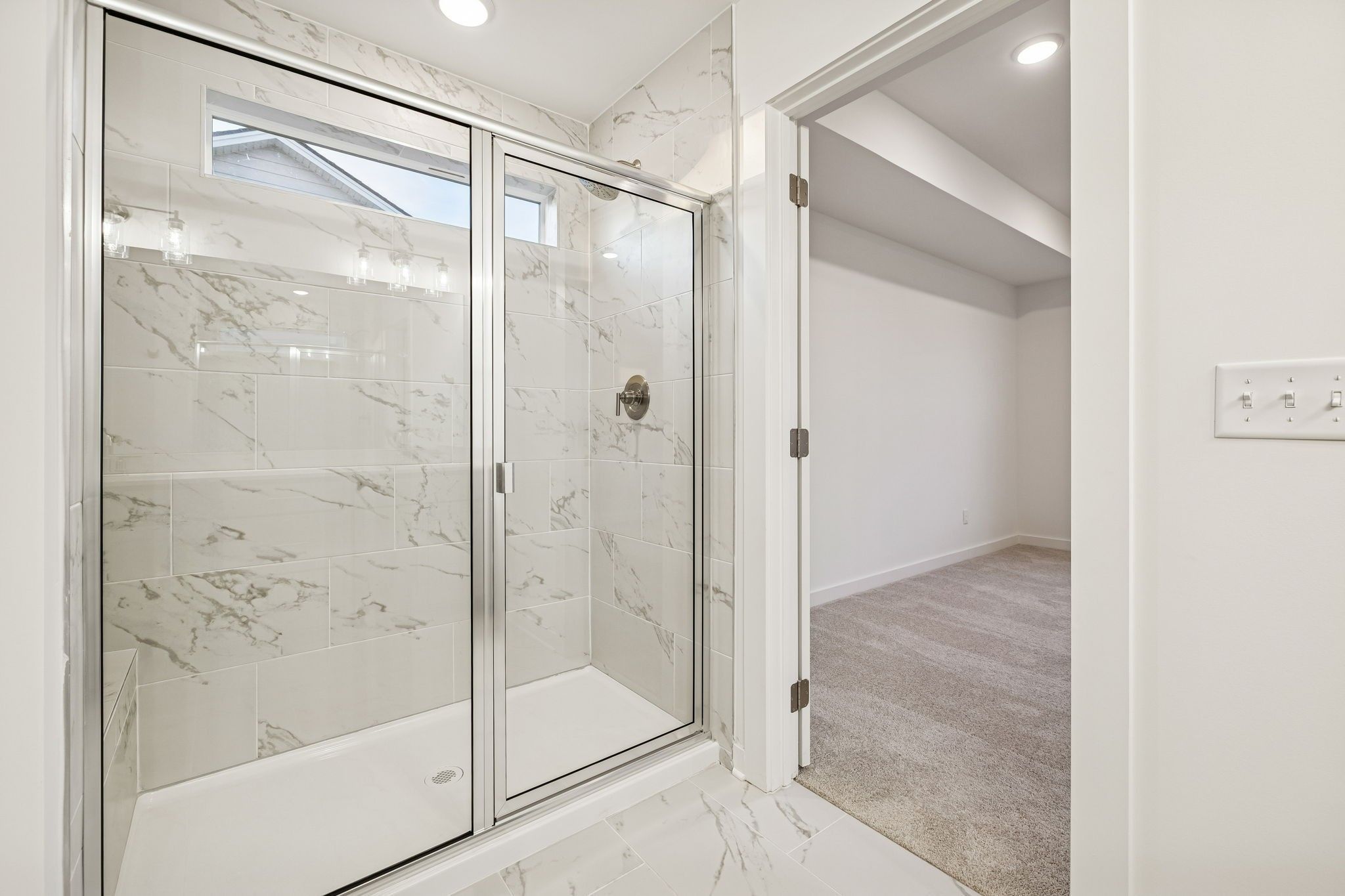 Elegant walk-in shower with white marble tiles, glass enclosure, and bench in master bath, Davidson Homes The Willow, White House TN