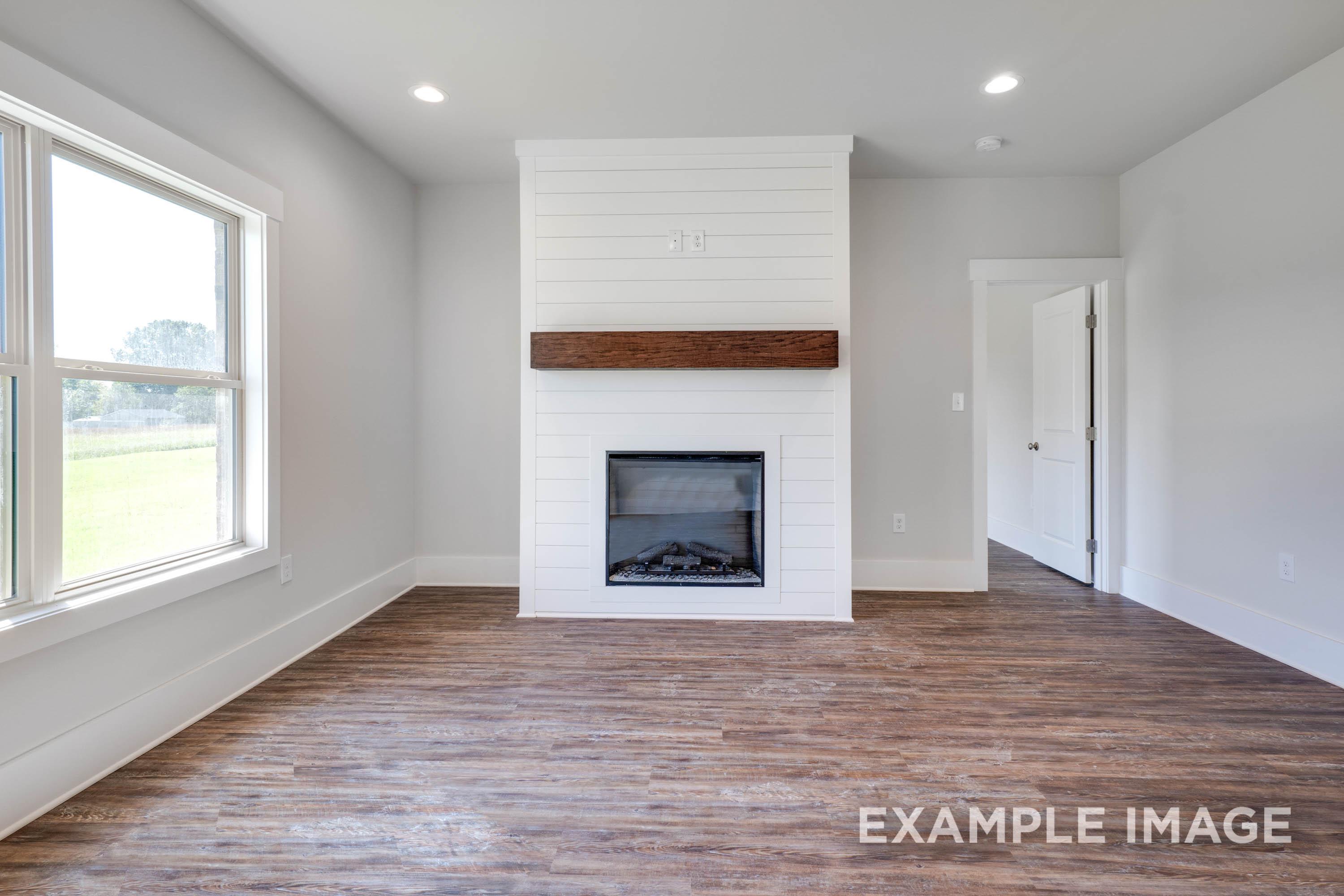Living room in The Richmond D featuring a white shiplap fireplace with a wood mantel and modern plank flooring.