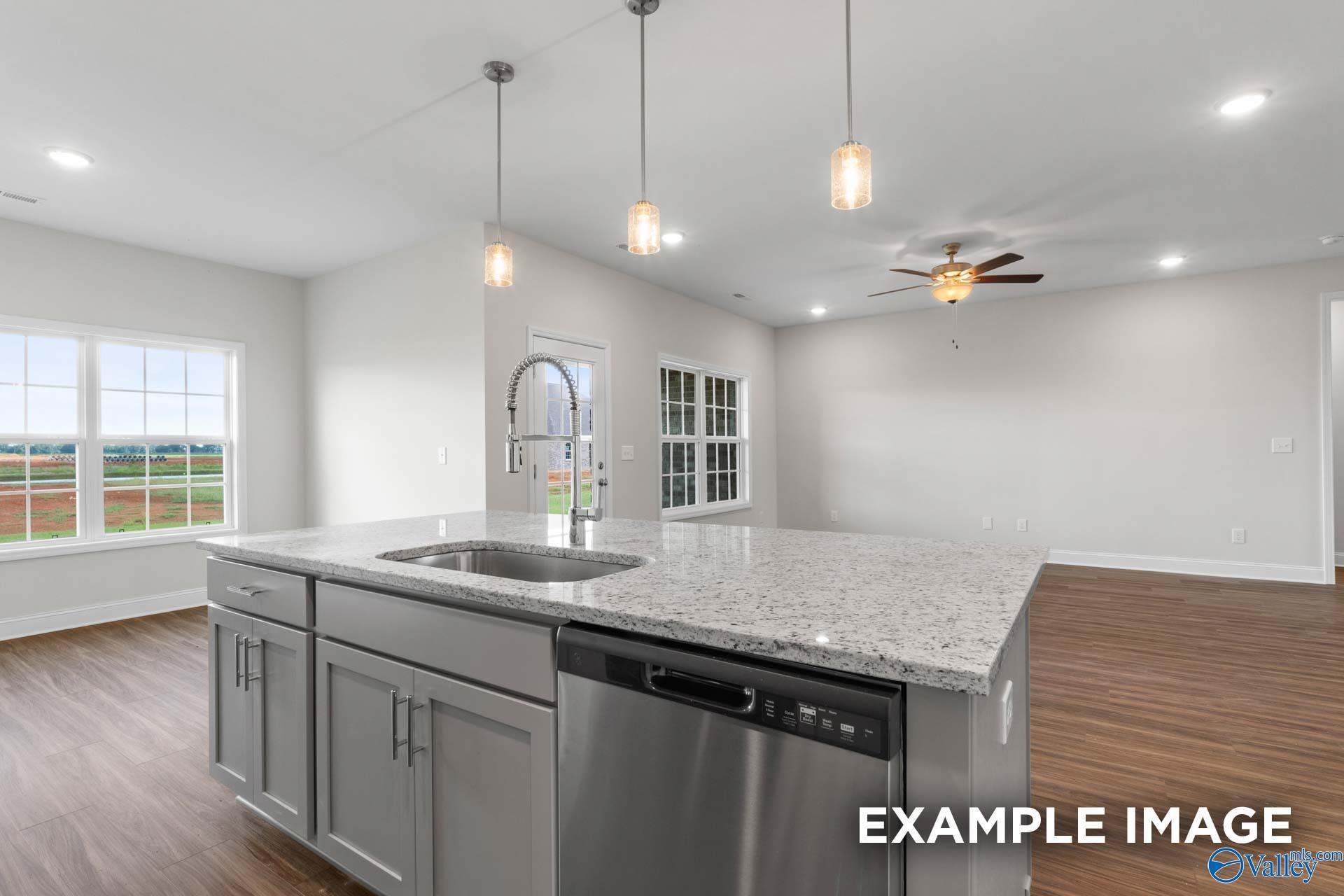 Modern open-concept kitchen featuring granite island, stainless dishwasher, and pendant lights in The Montgomery floor plan by Davidson Homes, Hartselle, Alabama
