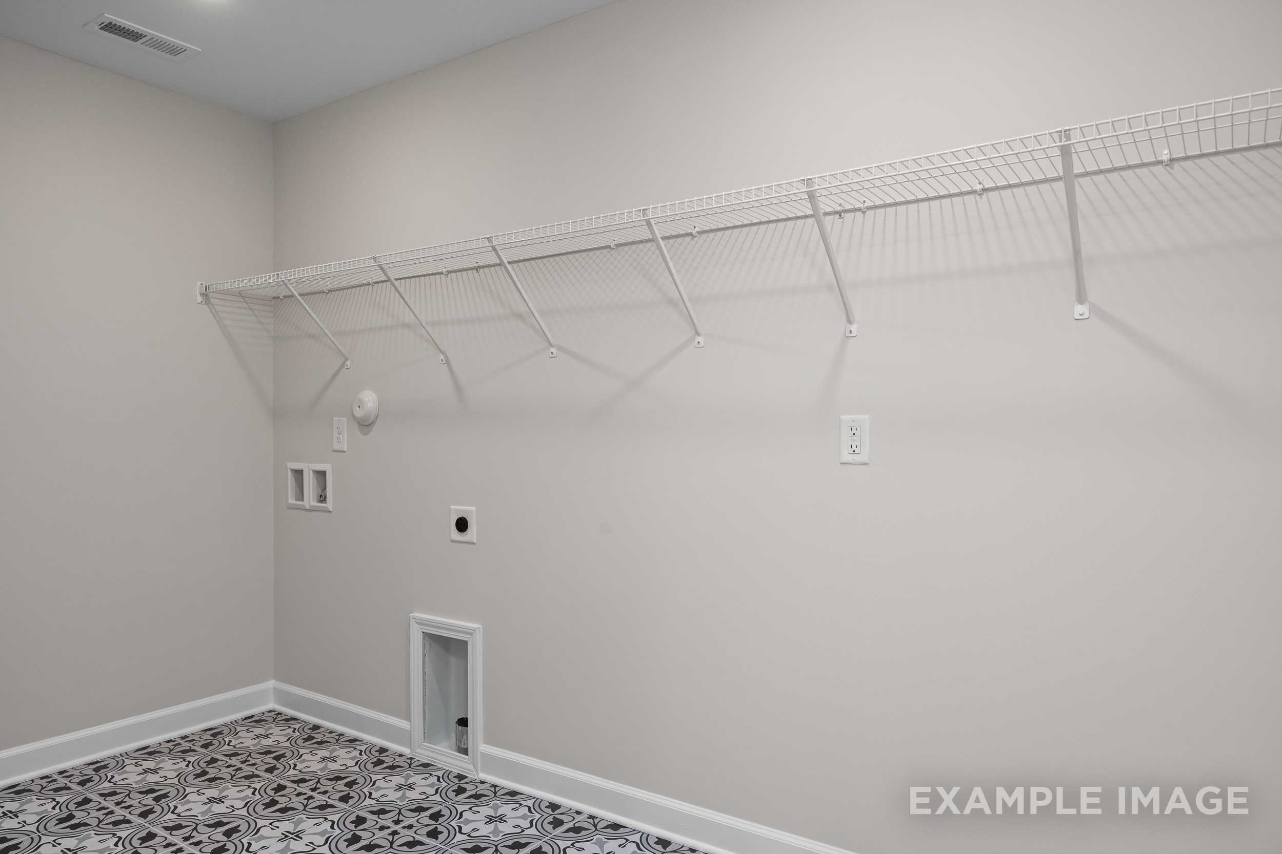 Spacious laundry room in The Hickory II with wire shelving, utility sink, tiled floor, and beige walls
