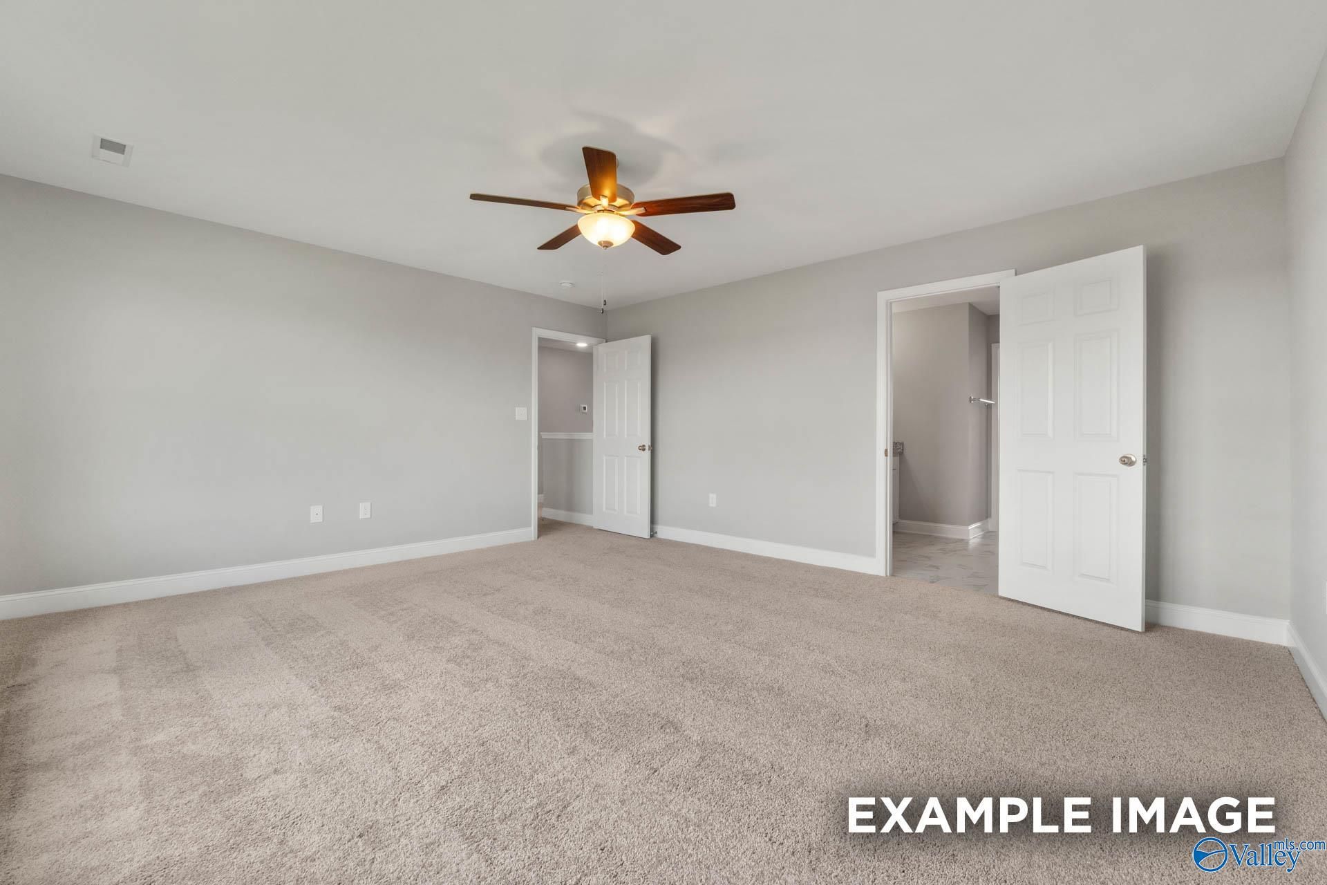 Spacious bedroom with light gray walls, beige carpet, ceiling fan, and adjacent bath door in Davidson Homes The Shelby B, Athens, Alabama