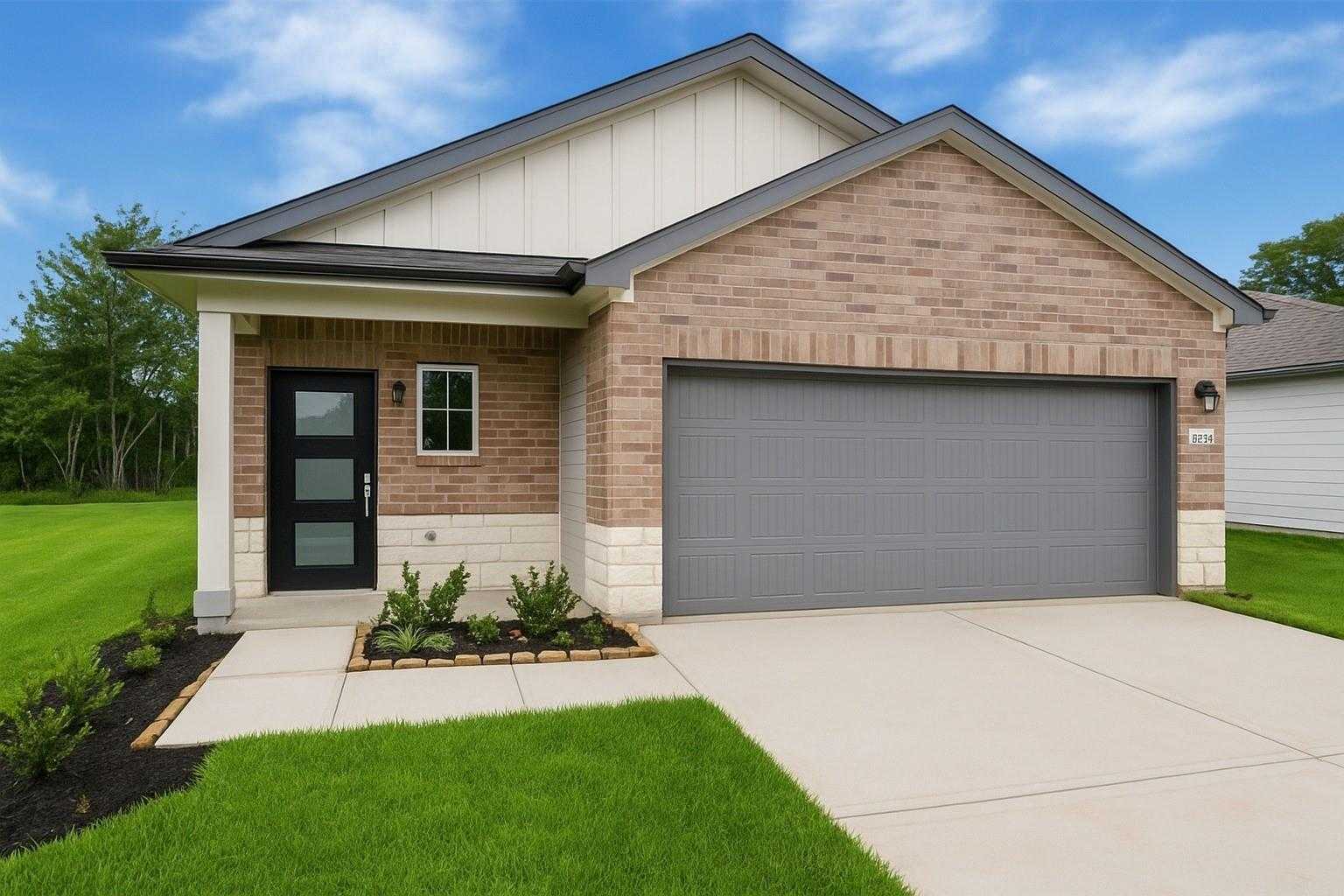 Modern 1-story brick home with 2-car garage, black front door, covered porch, and landscaped yard in Caney Creek Place, Conroe, Texas