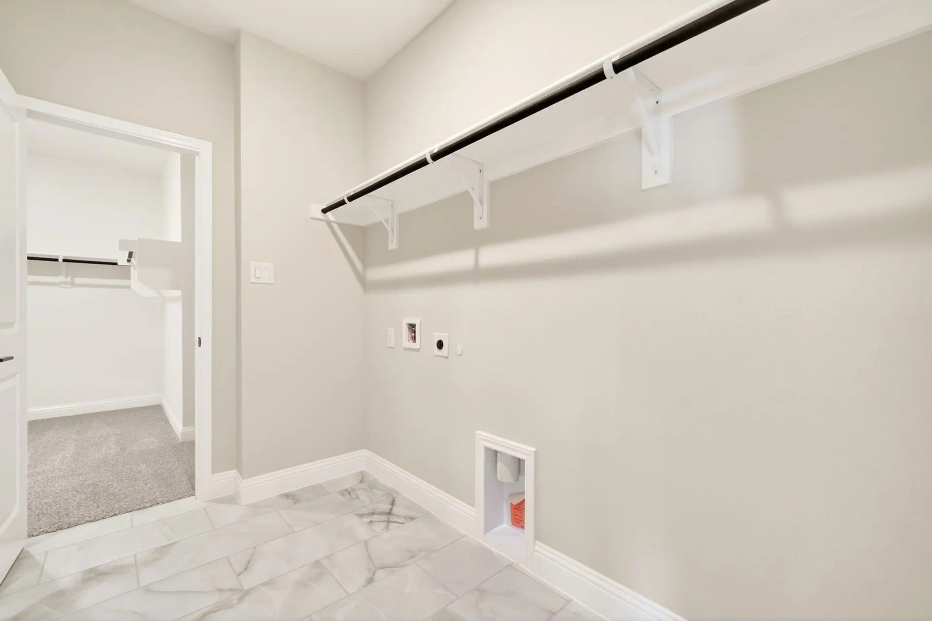 Laundry room with marble-look tile flooring and overhead shelving in The Holly C floor plan by Davidson Homes in Heartland.