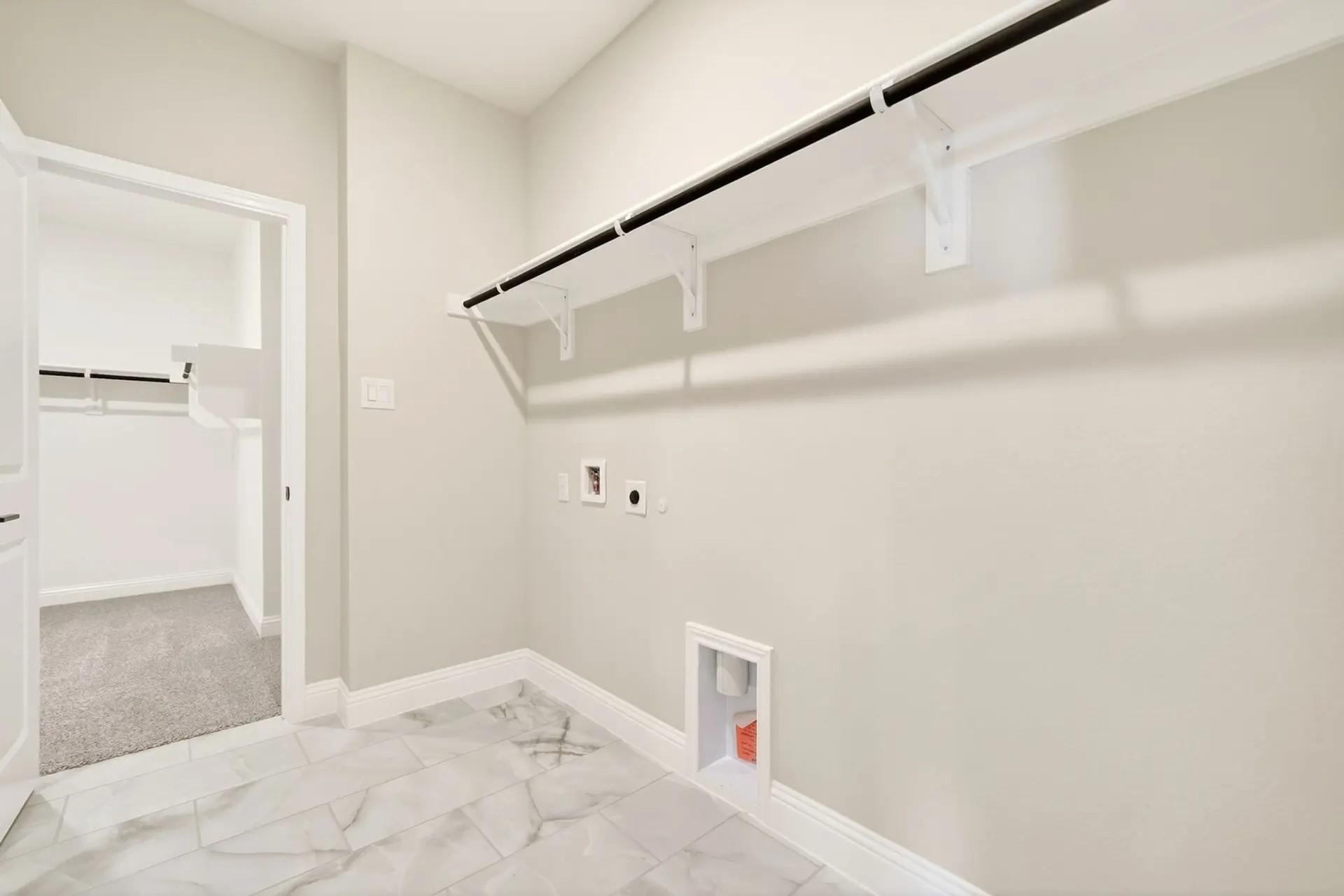 Laundry room with marble-look tile flooring and overhead shelving in The Holly C floor plan by Davidson Homes in Heartland.
