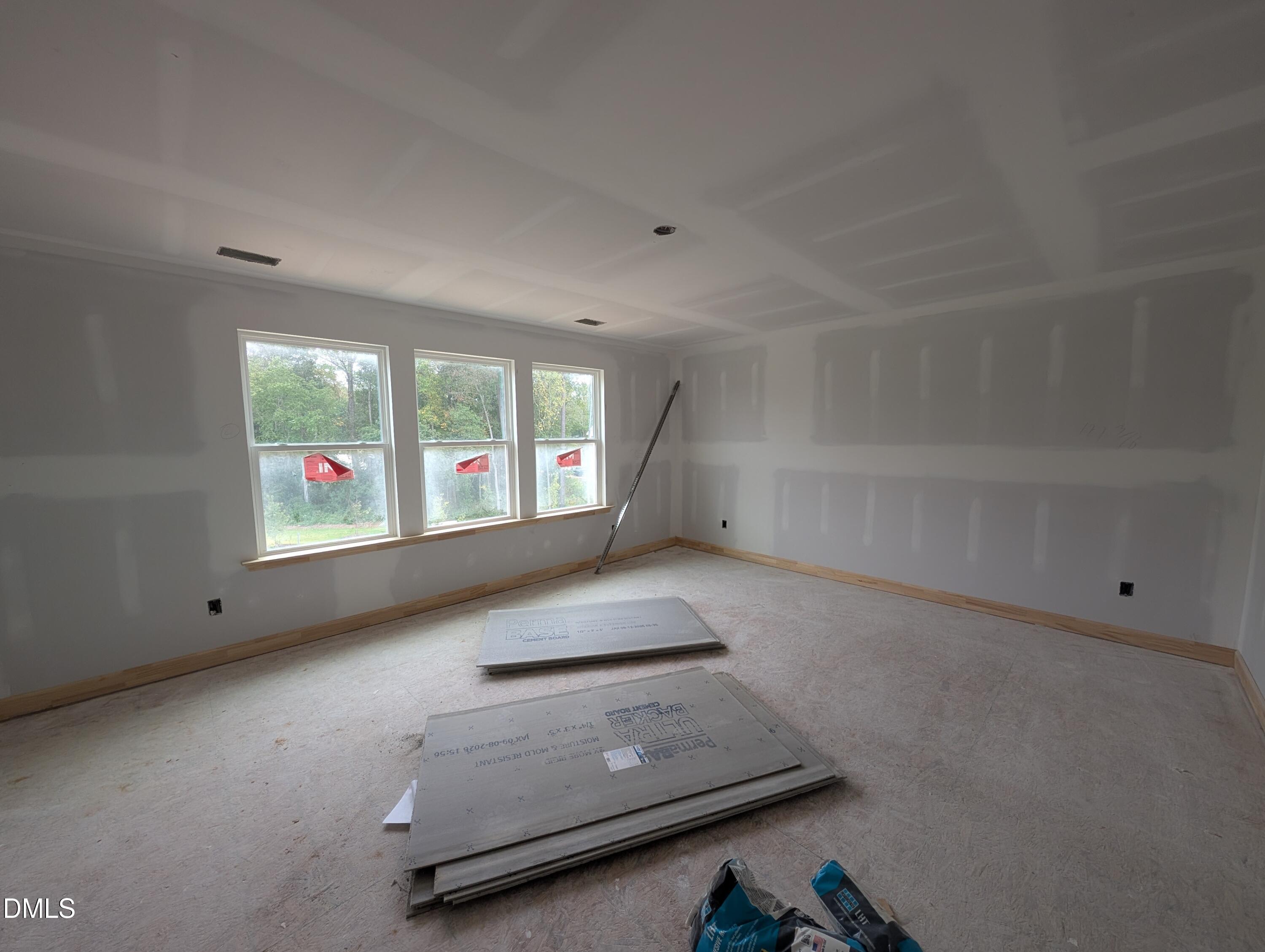 Unfinished spacious room with three windows and wood-trimmed sills under construction in Davidson Homes The Beech plan, Wendell Ridge, NC