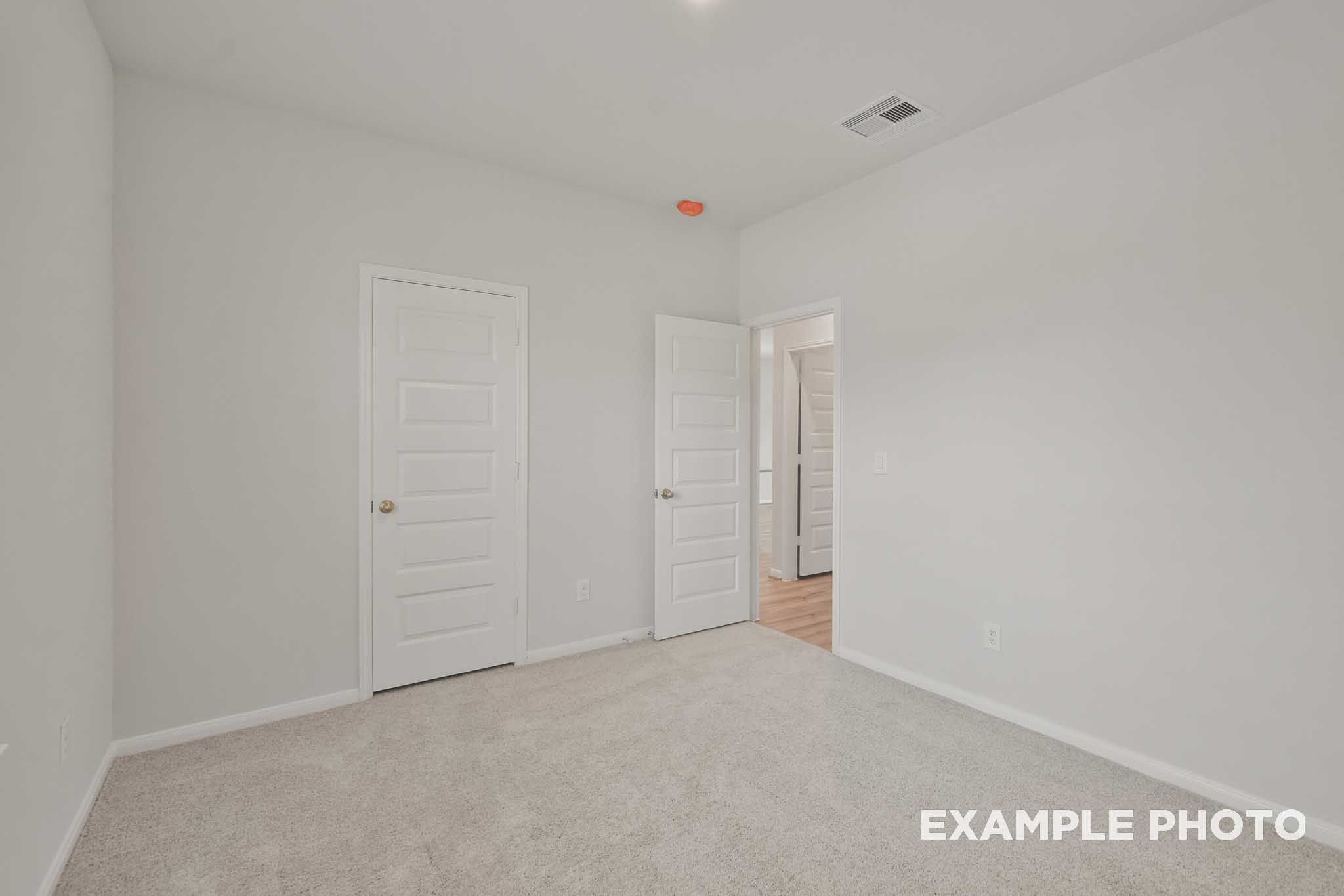 Spacious secondary bedroom in The Comal floor plan by Davidson Homes, neutral walls, carpeted floor, double doors to bath