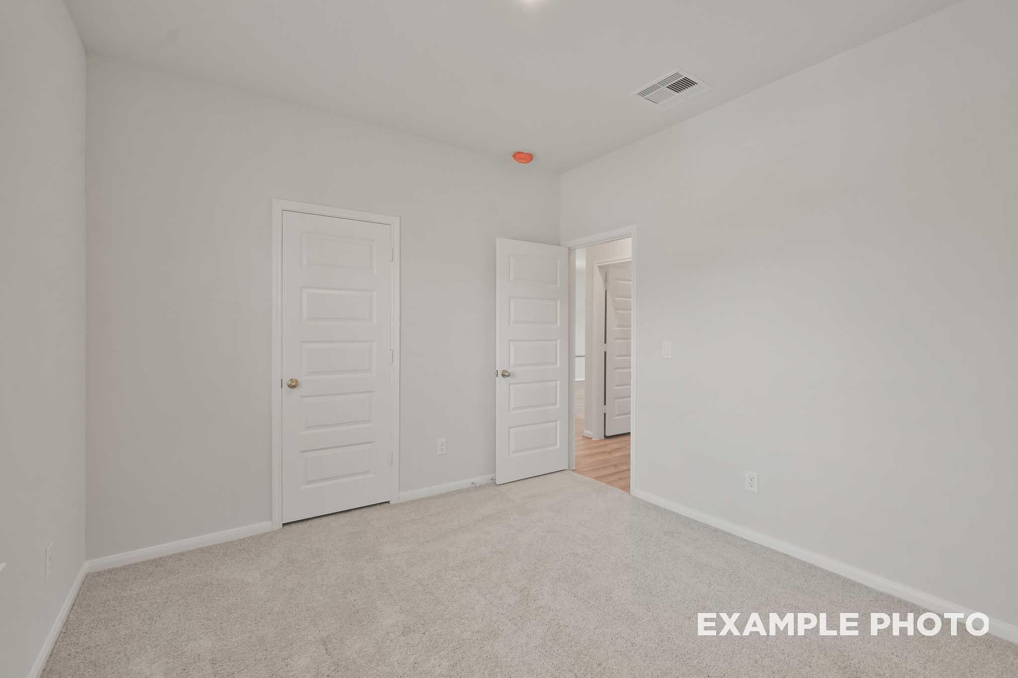Spacious secondary bedroom in The Comal floor plan by Davidson Homes, neutral walls, carpeted floor, double doors to bath
