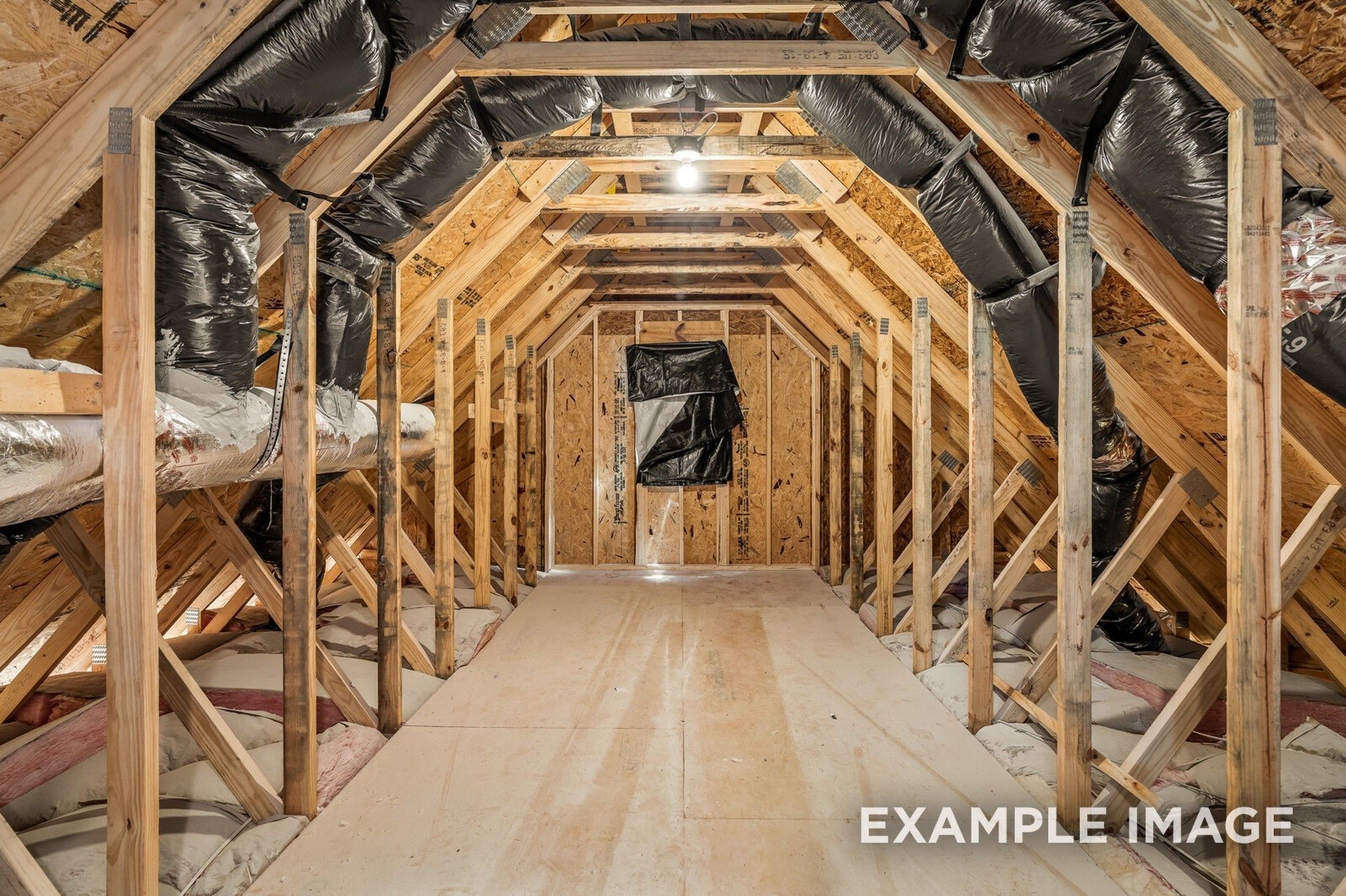 Exposed wooden rafters, black insulation, and HVAC ducts in unfinished attic of Davidson Homes The Ash A in Gallatin, Tennessee