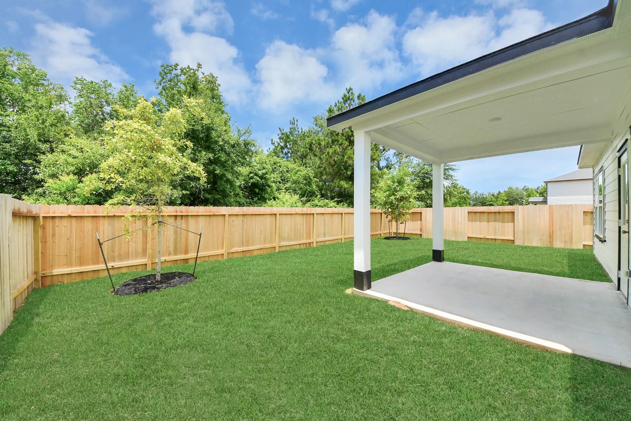 Covered concrete patio and private fenced backyard at The Blanco E floor plan in Caney Creek Place, Conroe, Texas.