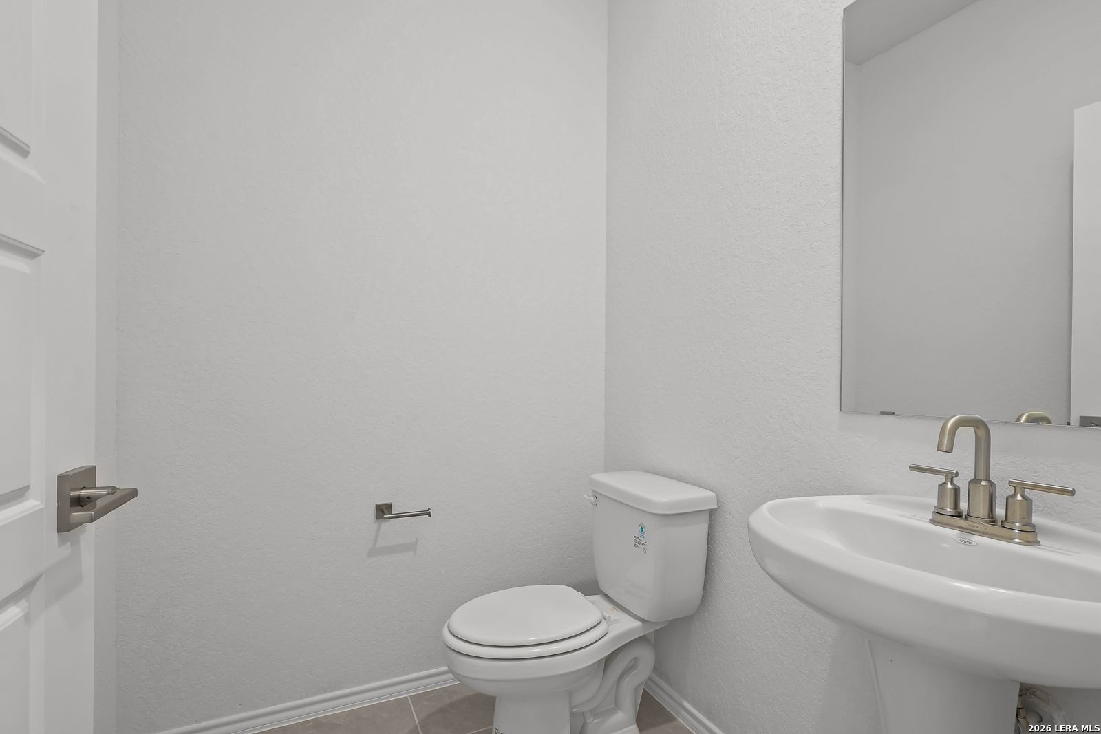 Modern white half bath with vanity sink, gold faucets, toilet, and mirrored cabinet in Davidson Homes Sequoia B, San Antonio
