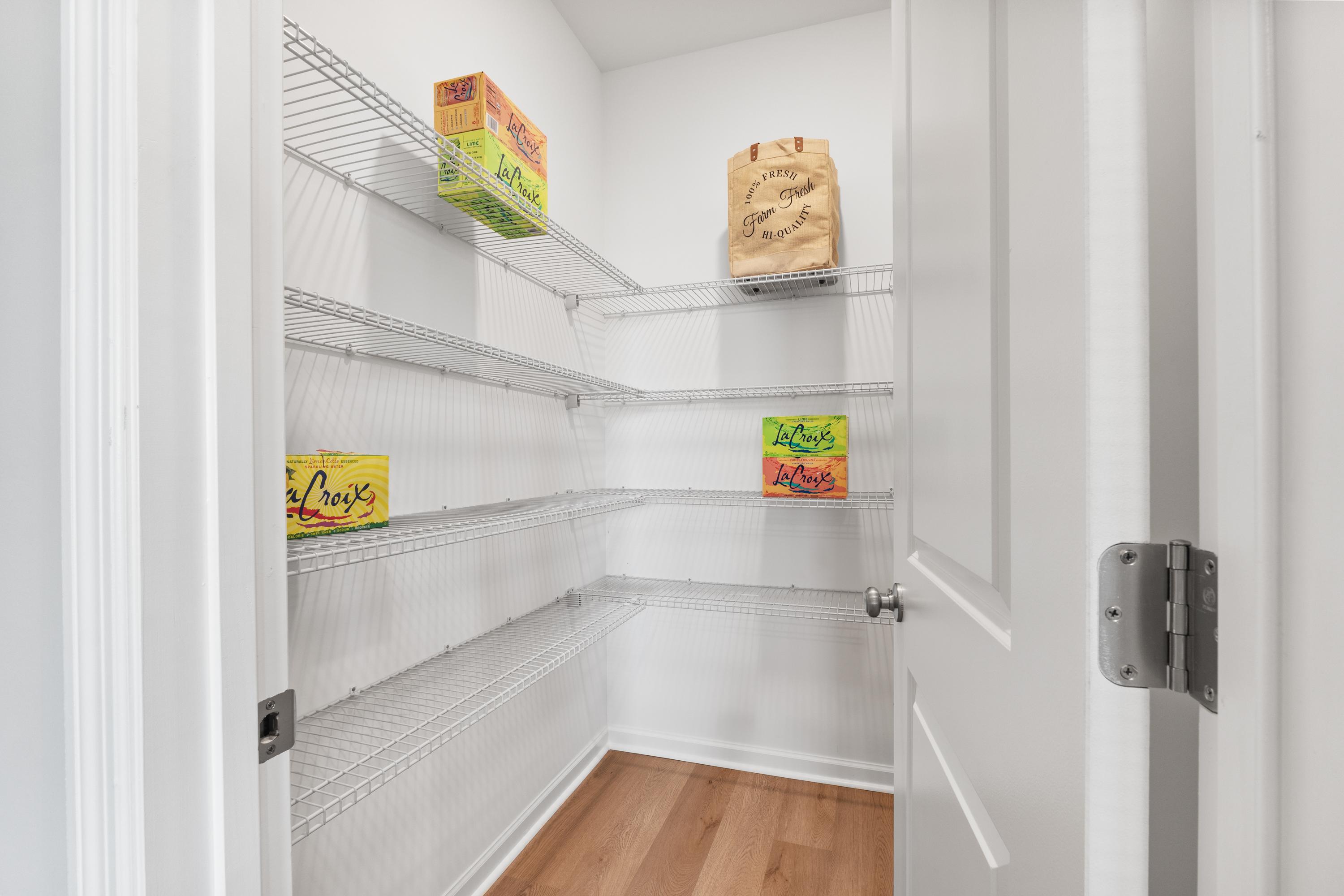 Spacious walk-in pantry with wire shelving stocked with Cheerios boxes at The Meadows at Hampton Cove, Owens Cross Roads AL