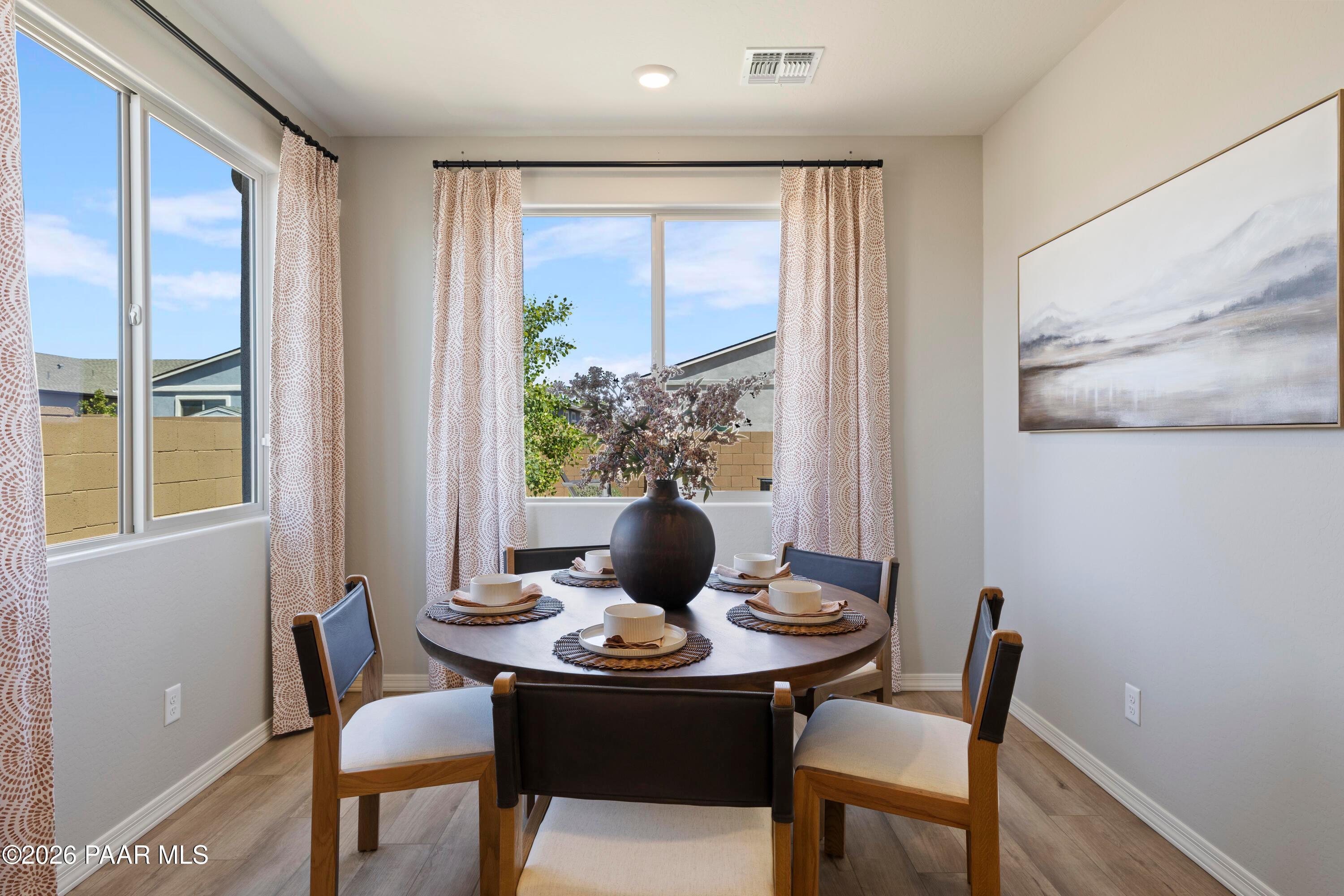 Bright dining area with round wood table in The Harmony A floor plan at North Ridge, Pronghorn Ranch, Prescott Valley.