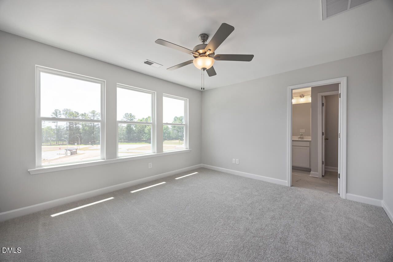 Bright bedroom with ceiling fan and en suite bathroom in The Mitchell floor plan at Camden Park, Knightdale, NC.