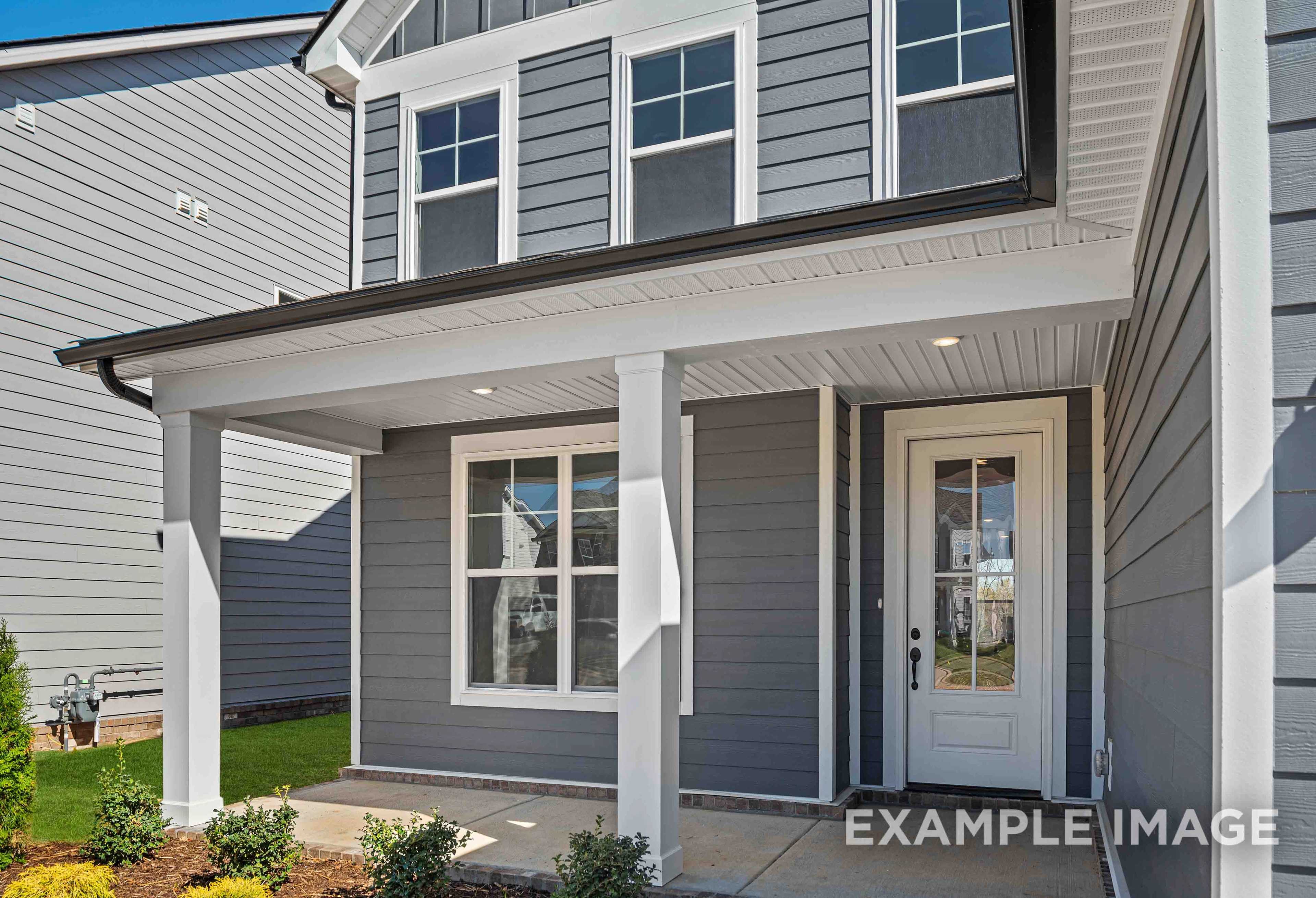 Two-story The Ash home elevation featuring gray siding, covered front porch with white columns, and glass-paneled door in Mt. Juliet