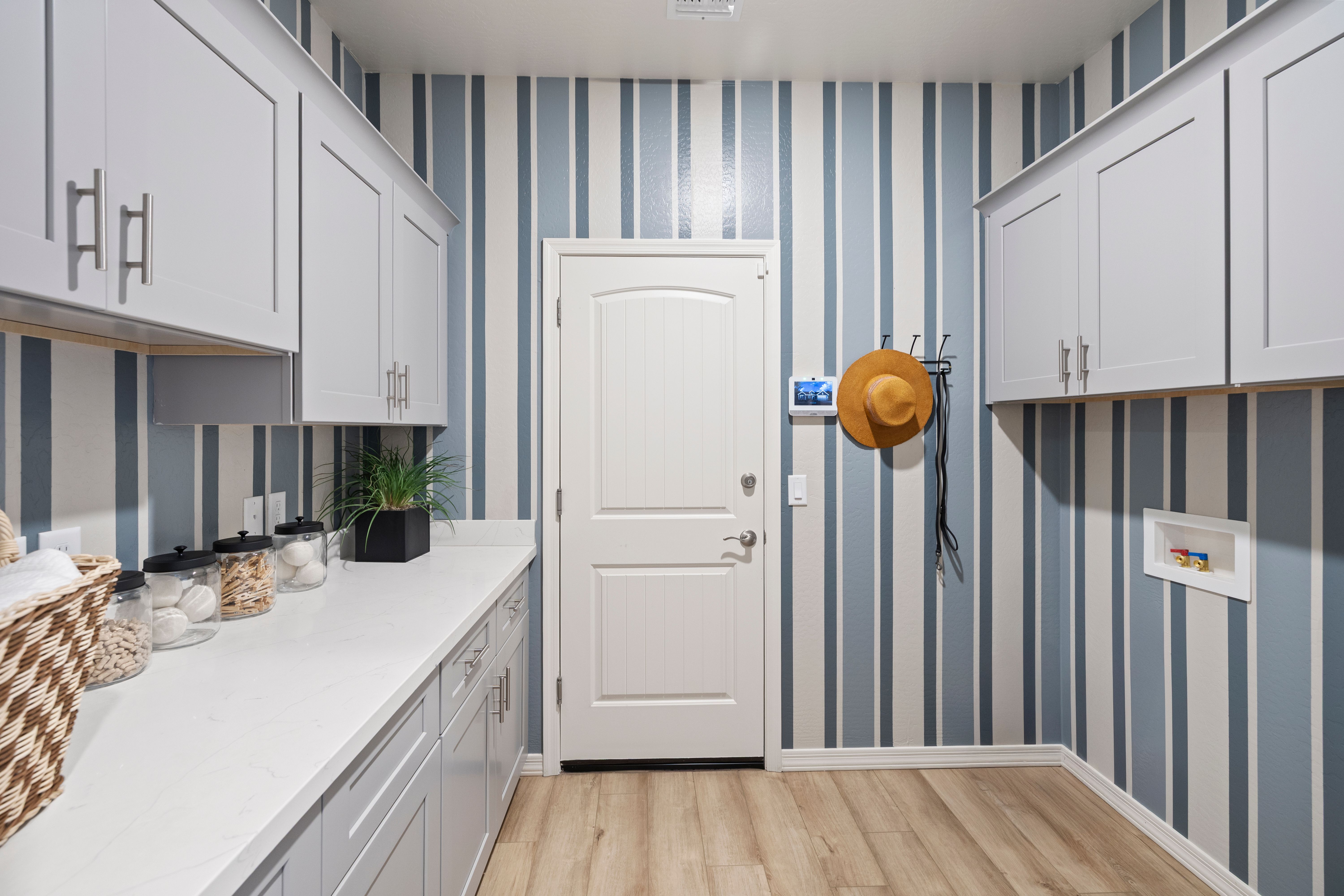Spacious laundry room at North Ridge Pronghorn Ranch Prescott Valley AZ with gray shaker cabinets, blue striped walls, quartz counters