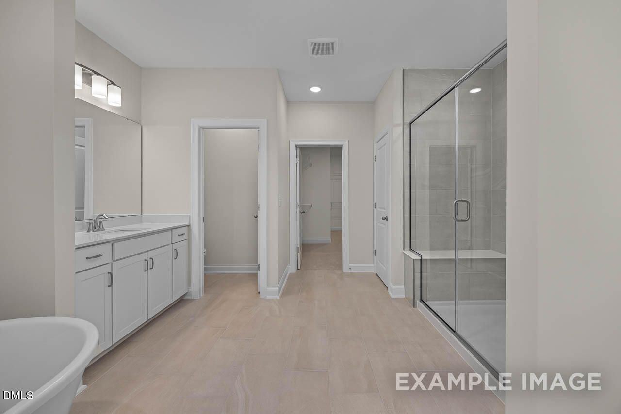 Elegant master bathroom featuring double vanity, freestanding tub, and frameless glass shower in Davidson Homes The Aspen C, Apex, NC