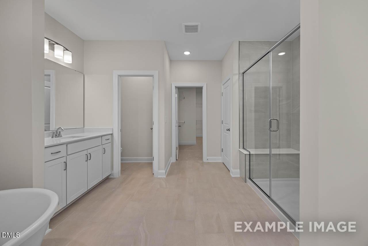 Modern primary bathroom with walk-in shower, dual vanity, and neutral tile in The Aspen C floor plan, Ashland, Apex, NC.