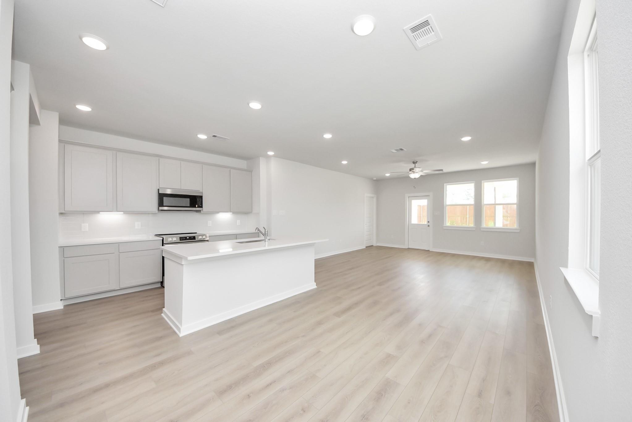 Modern open-concept kitchen and living area in The Blanco F floor plan at Spring Branch Crossing, Conroe, Texas.