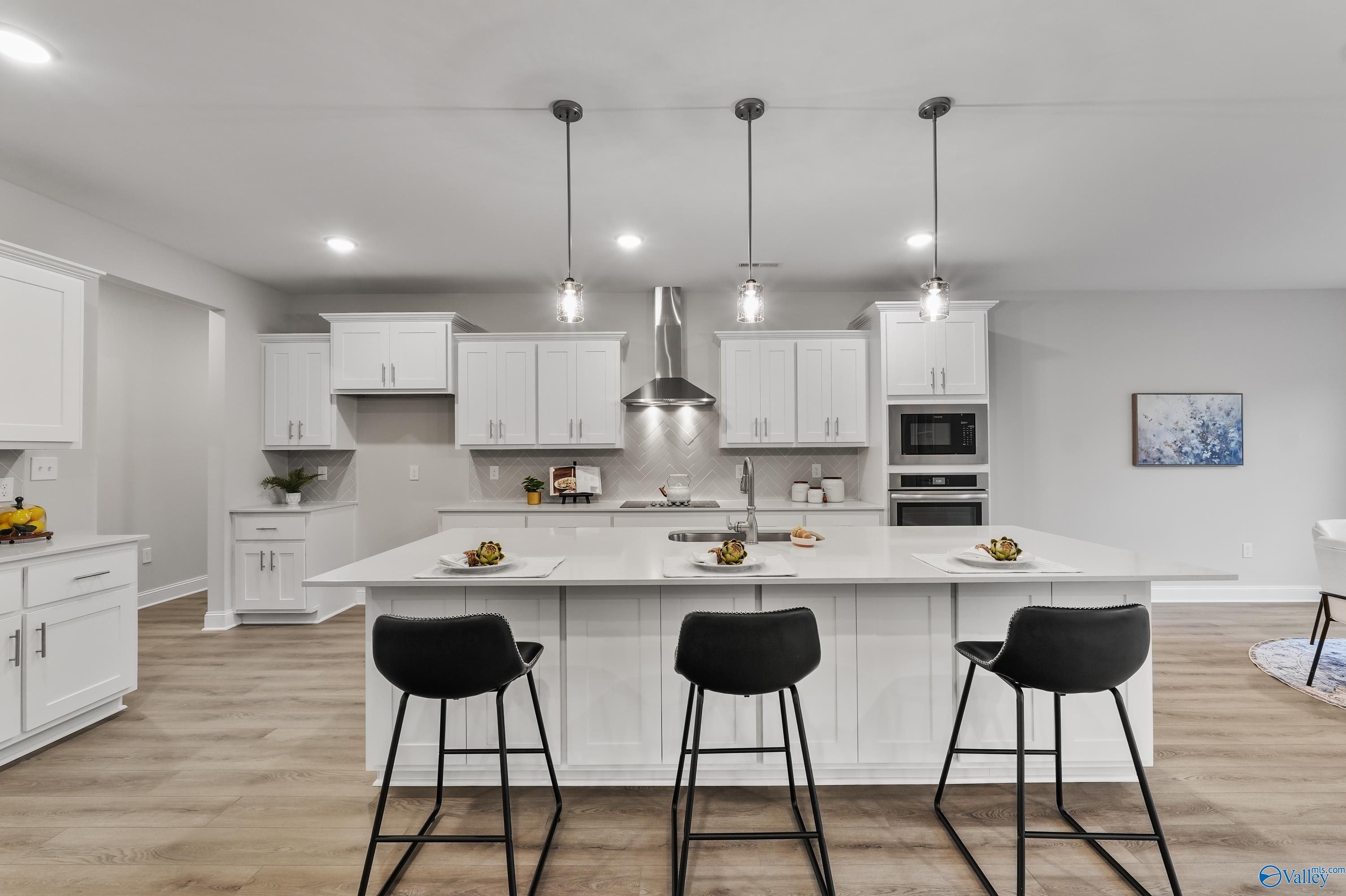 Modern open-concept kitchen with white island, stainless steel appliances, pendant lights in The Finleigh by Davidson Homes, Toney, AL