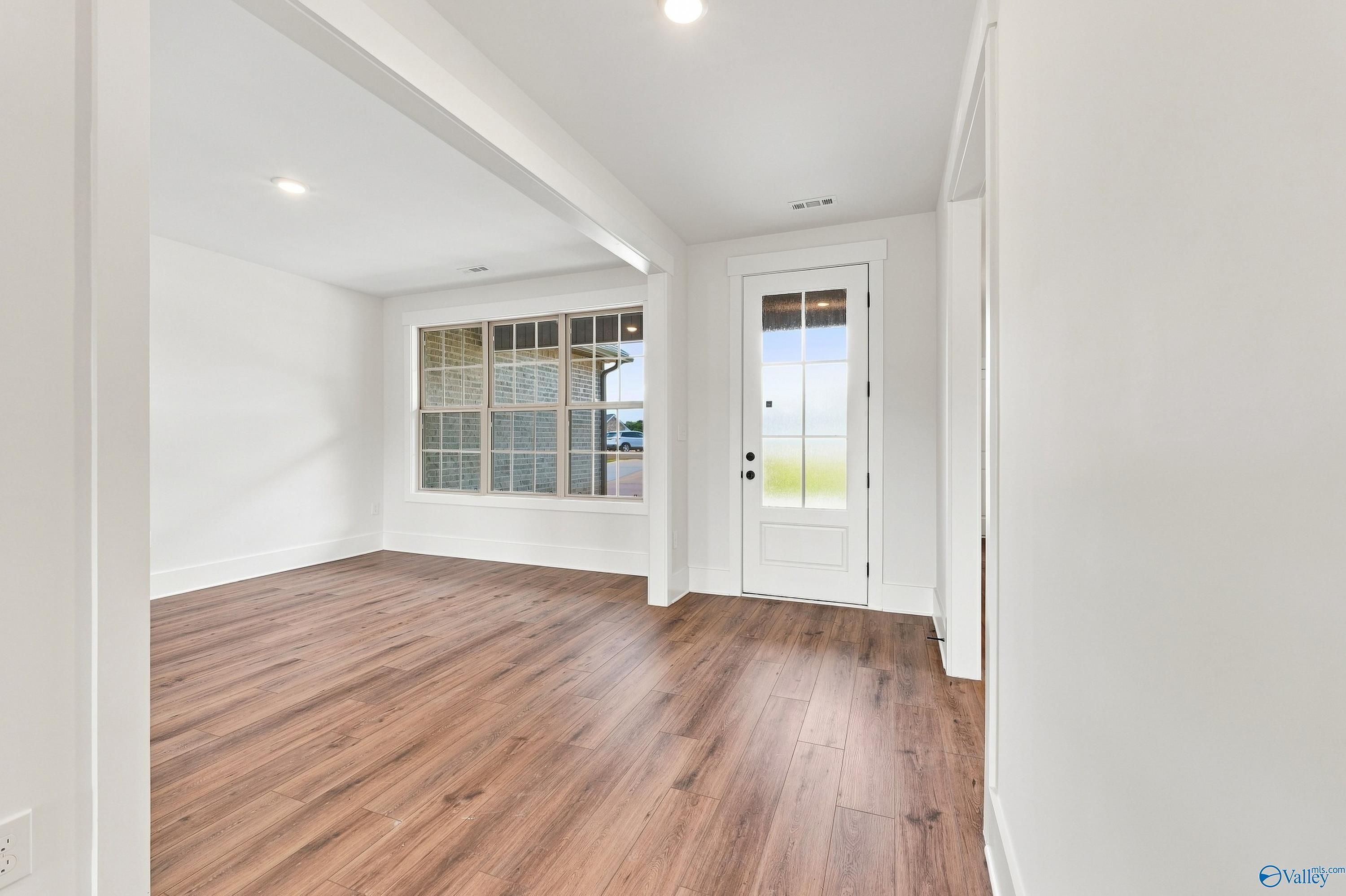 Bright entryway and dining area with luxury vinyl plank flooring, glass-panel front door, and large windows in Davidson Homes' Valencia floor plan at Riverton Preserve, Huntsville, Alabama.